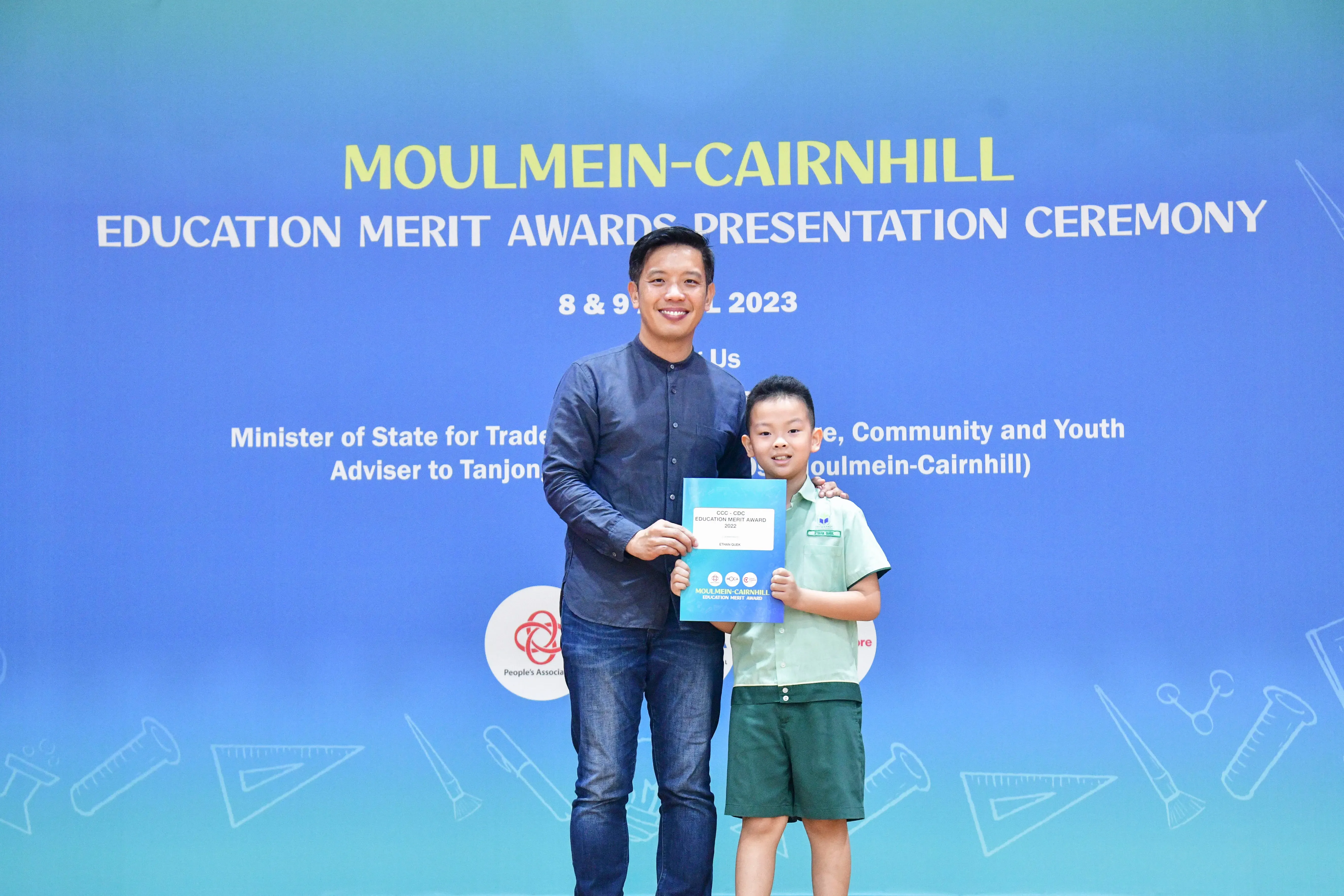 A man and a young boy hold a certificate together at the Moulmein-Cairnhill Education Merit Awards Ceremony 2023.