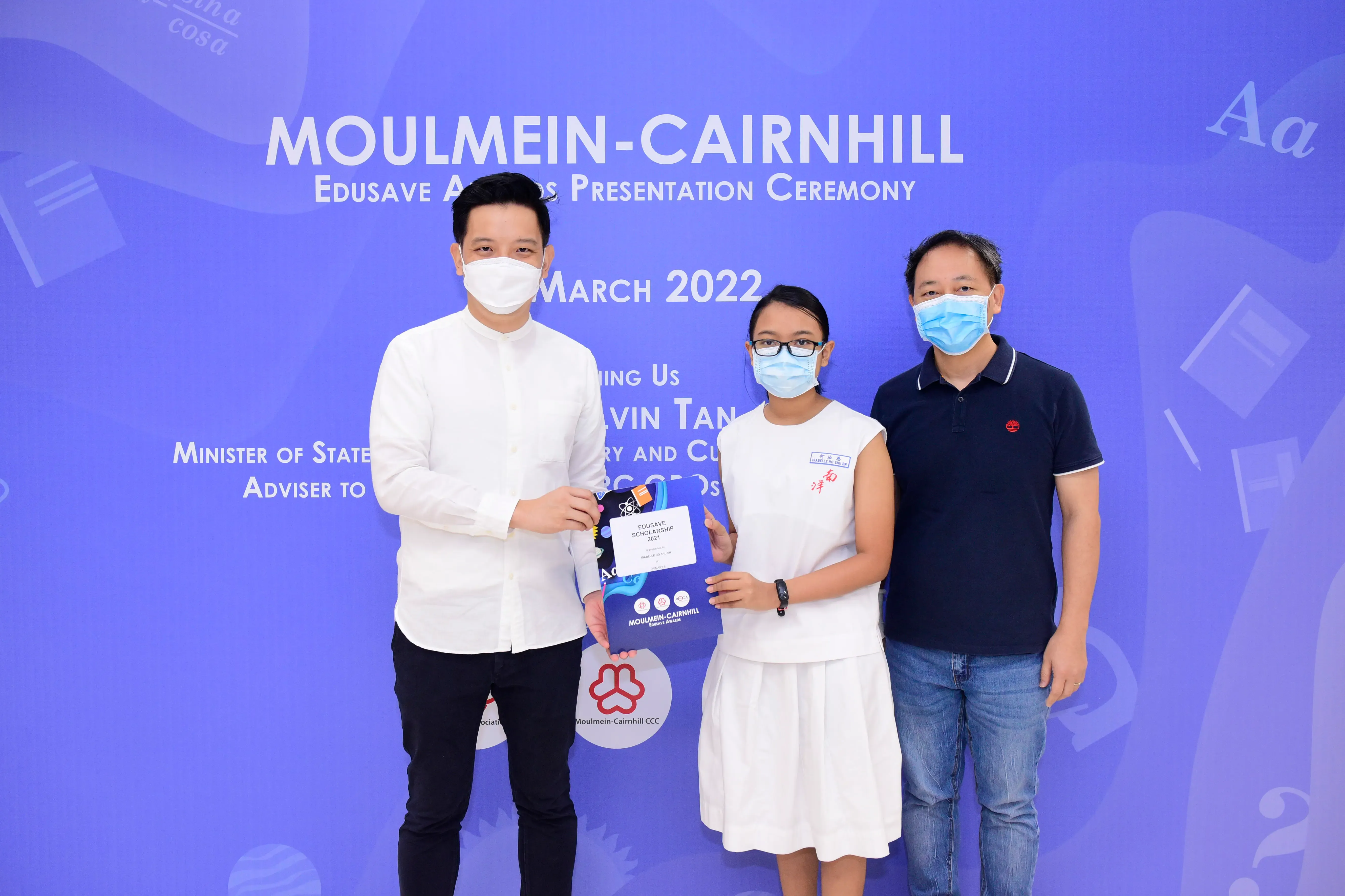 Three masked people pose at the Moulmein-Cairnhill Edusave Awards Presentation Ceremony in March 2022.