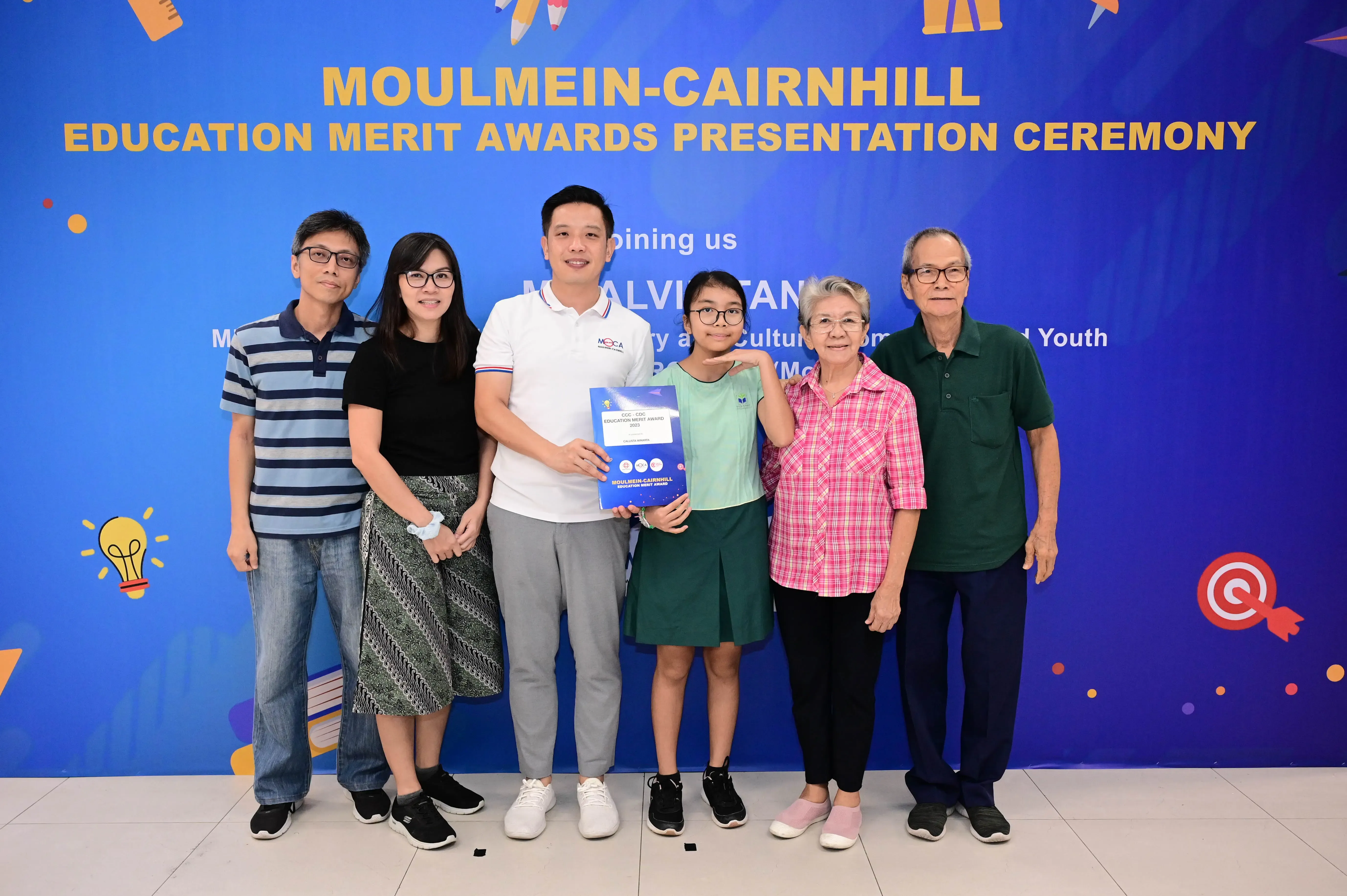 Six people pose holding an award booklet at the Moulmein-Cairnhill Education Merit Awards Presentation Ceremony.