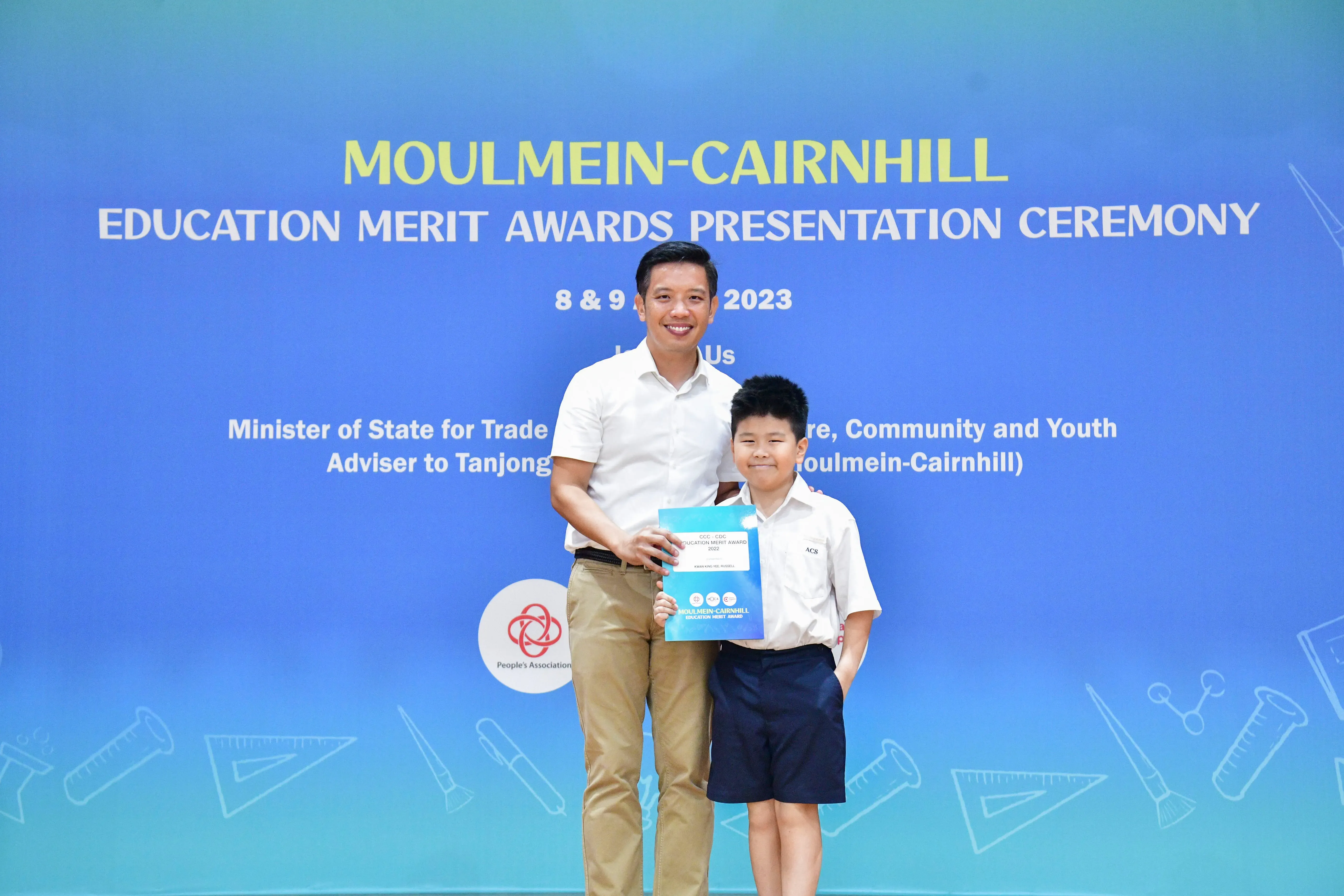 Man and young boy holding a certificate at the Moulmein-Cairnhill Education Merit Awards Ceremony 2023.
