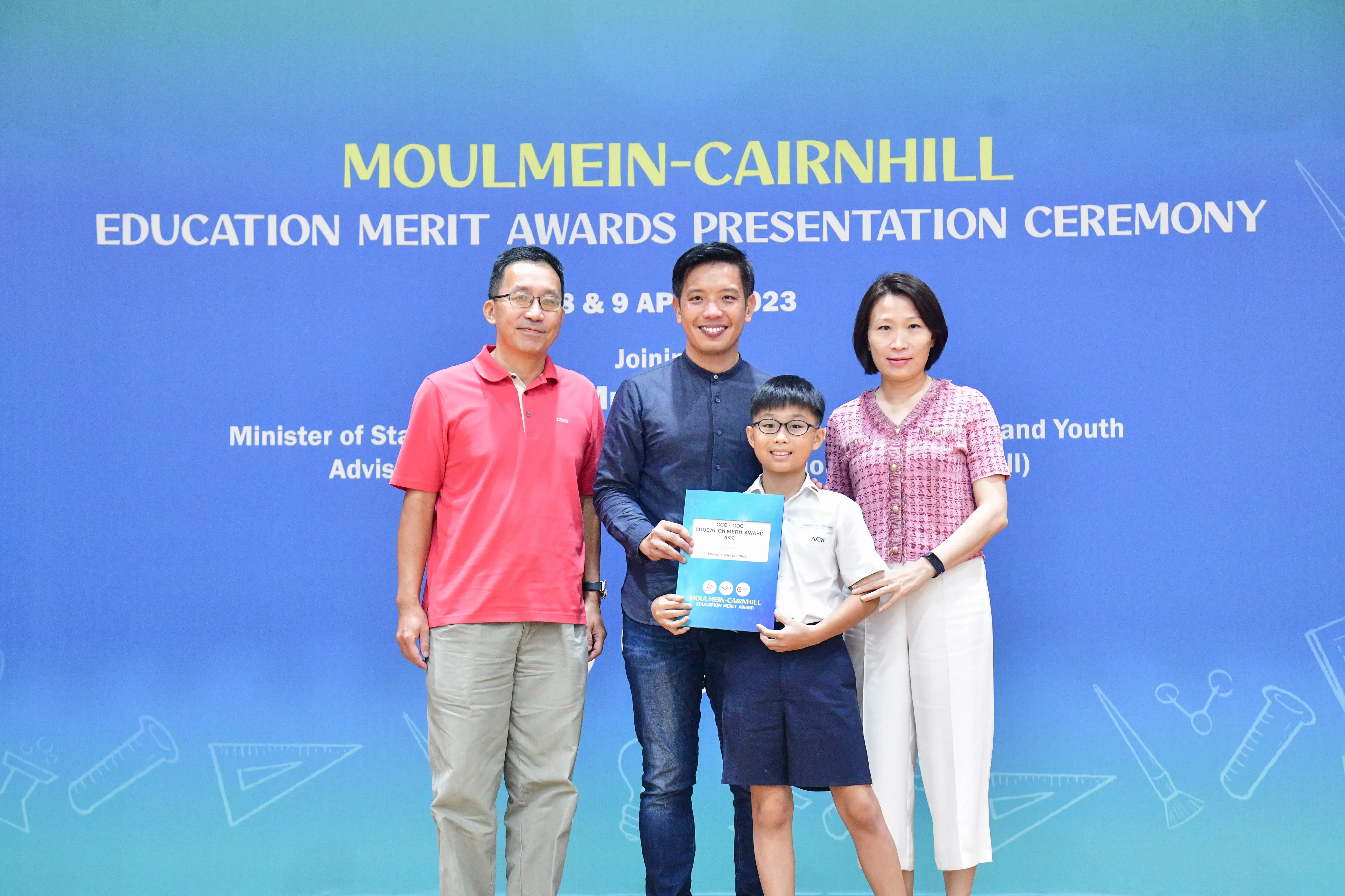 Three adults and a boy pose with an award certificate at the Moulmein-Cairnhill Education Merit Awards Ceremony 2023.