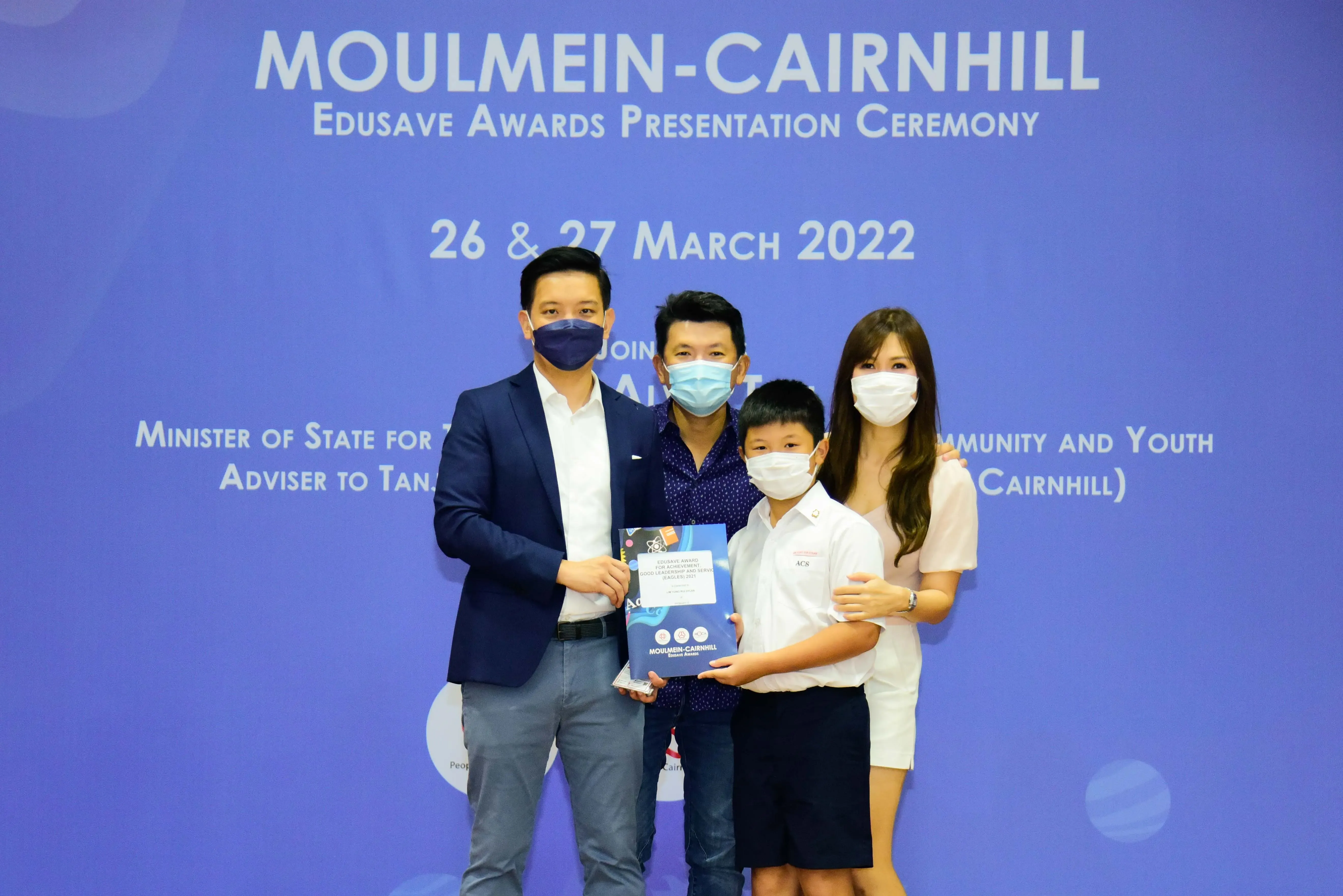 Four masked people pose at the Moulmein-Cairnhill Edusave Awards Presentation Ceremony on 26-27 March 2022.