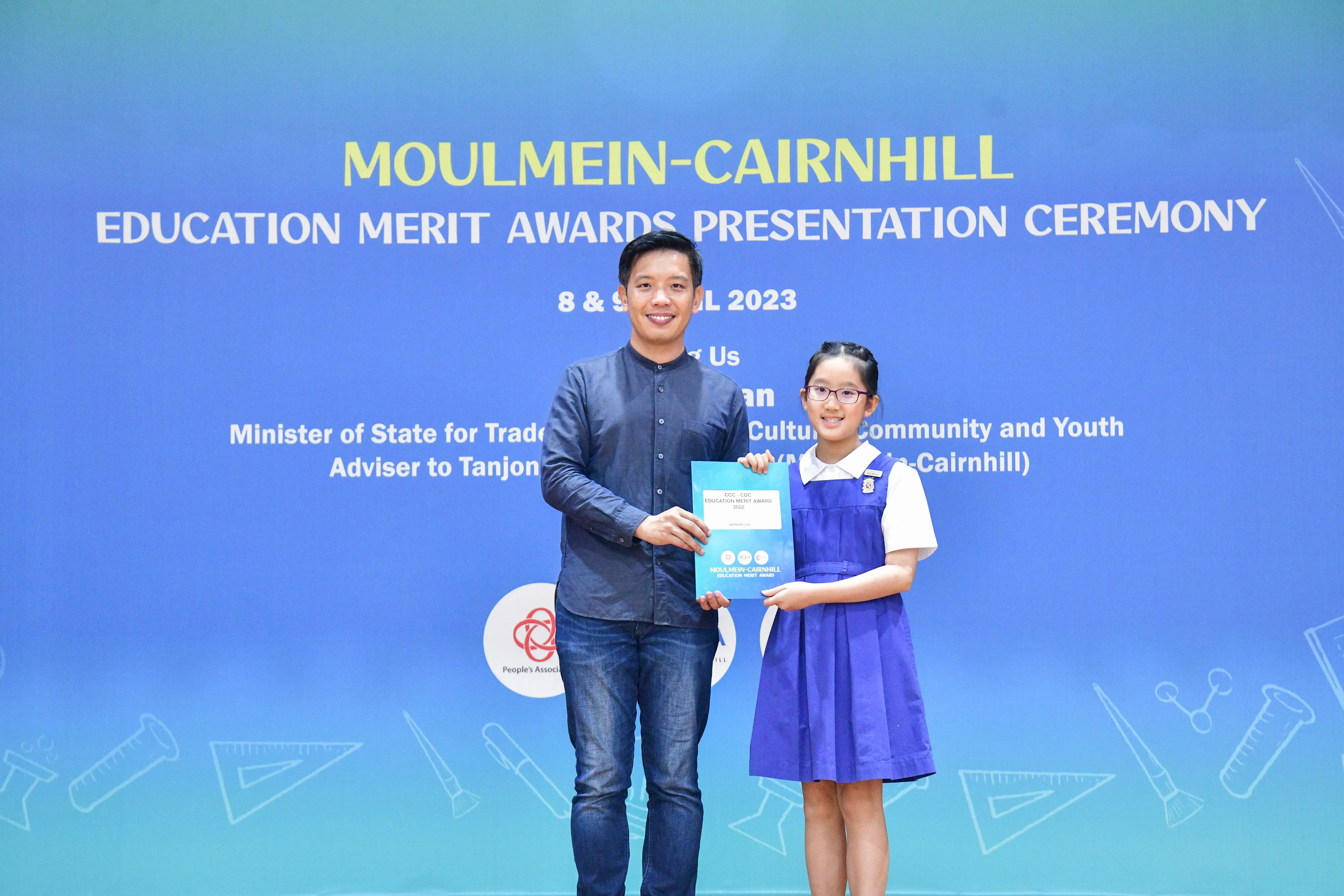 A man and a young girl in school uniform hold a certificate at the Moulmein-Cairnhill Education Merit Awards 2023.