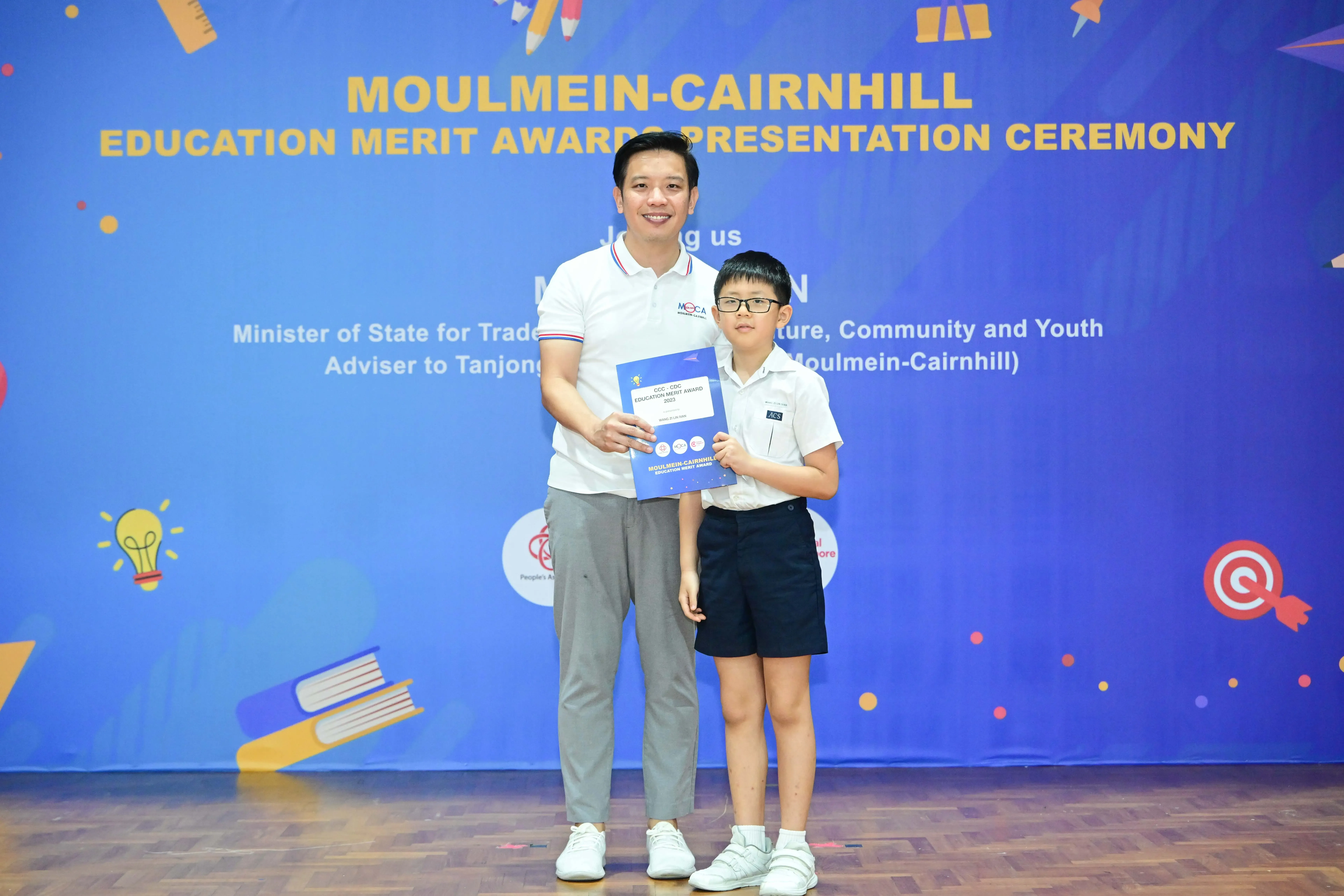 Man and young boy holding an award certificate at Moulmein-Cairnhill Education Merit Awards Presentation Ceremony.