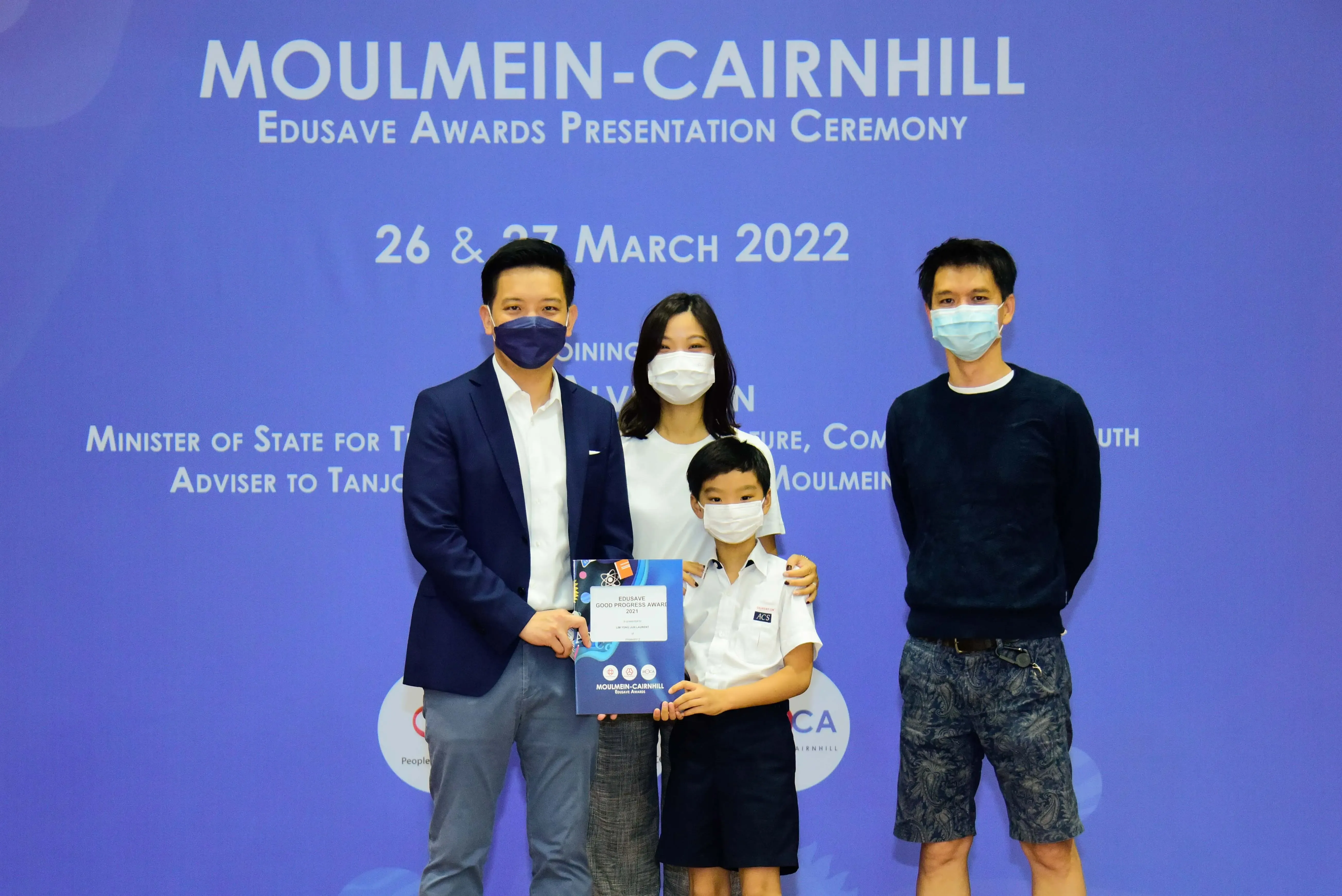 Four masked people pose at the Moulmein-Cairnhill Edusave Awards Presentation Ceremony on 26 March 2022.