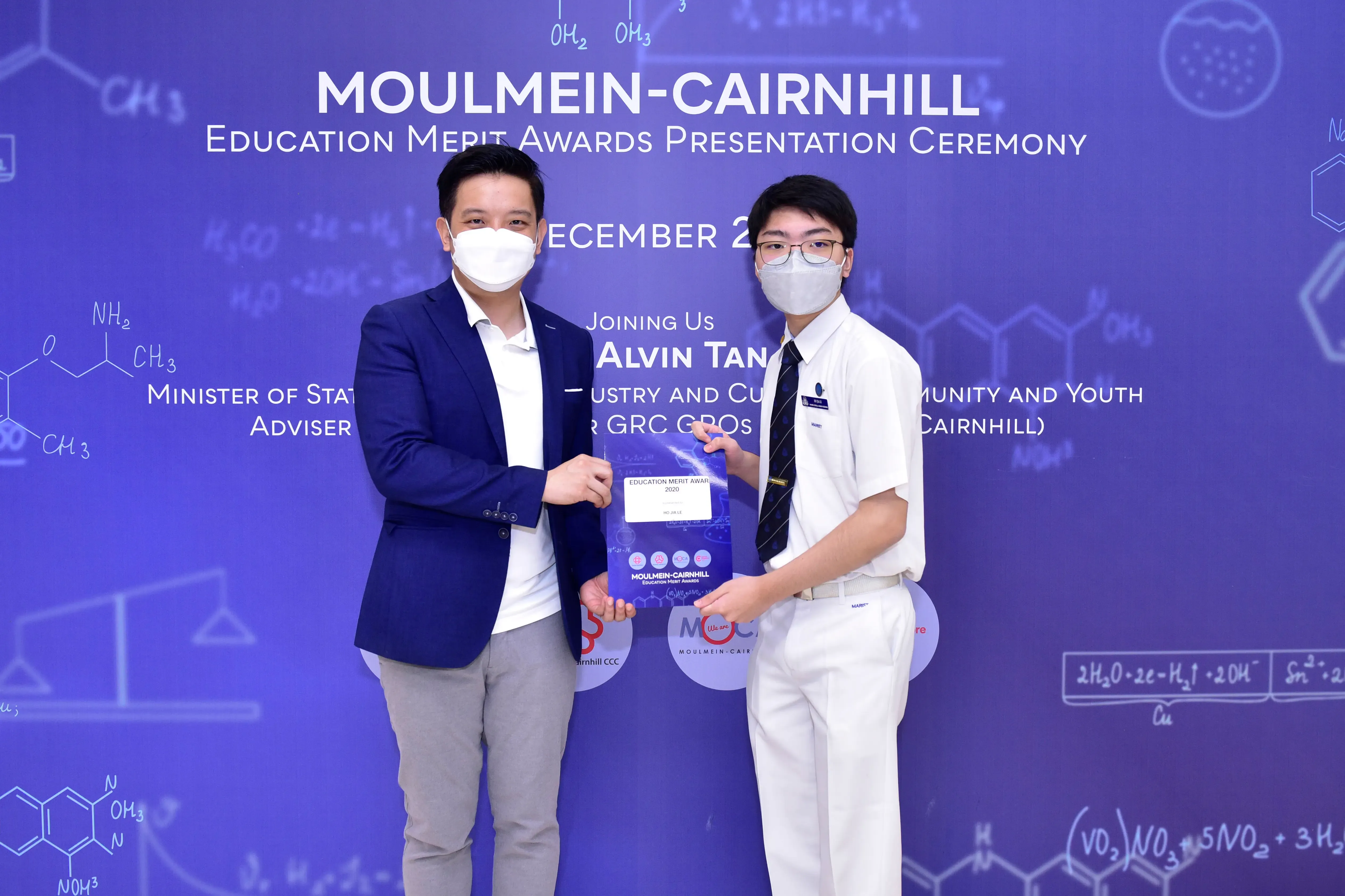 Two masked individuals pose together holding an award at the Moulmein-Cairnhill Education Merit Awards Ceremony.