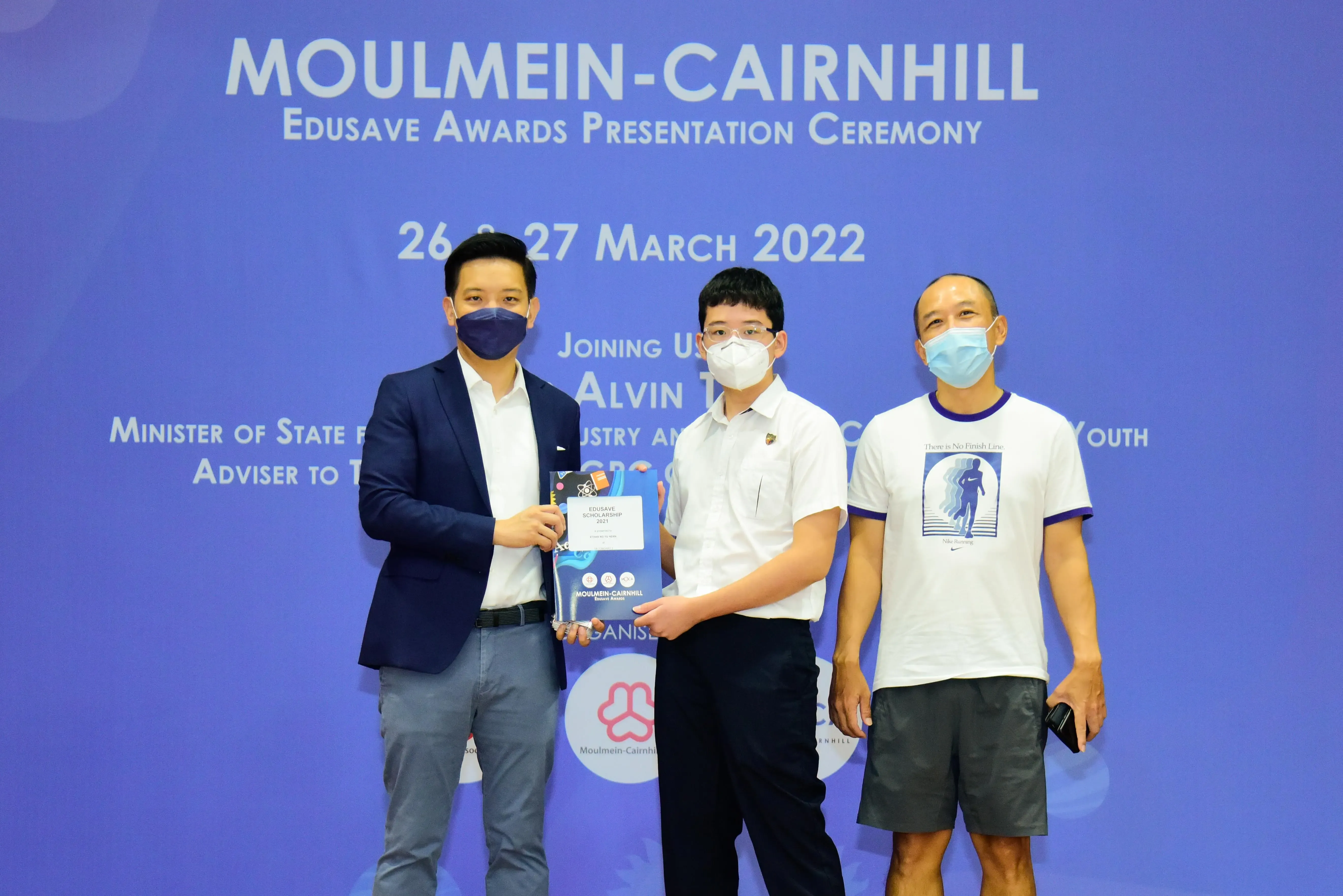 Three masked men pose at the Moulmein-Cairnhill Edusave Awards Presentation Ceremony on 27 March 2022.