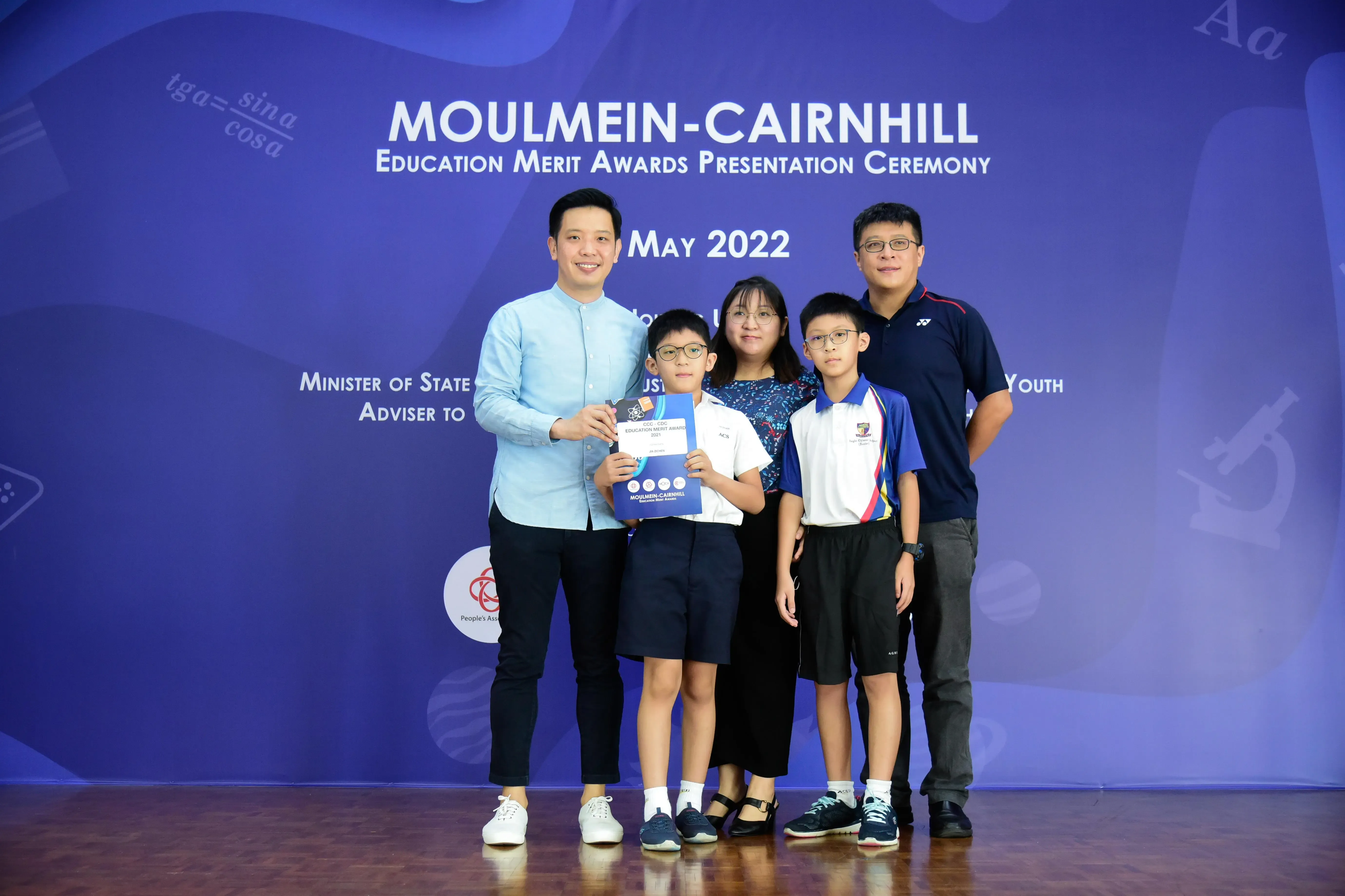 Five people pose at the Moulmein-Cairnhill Education Merit Awards Presentation Ceremony, May 2022 backdrop.