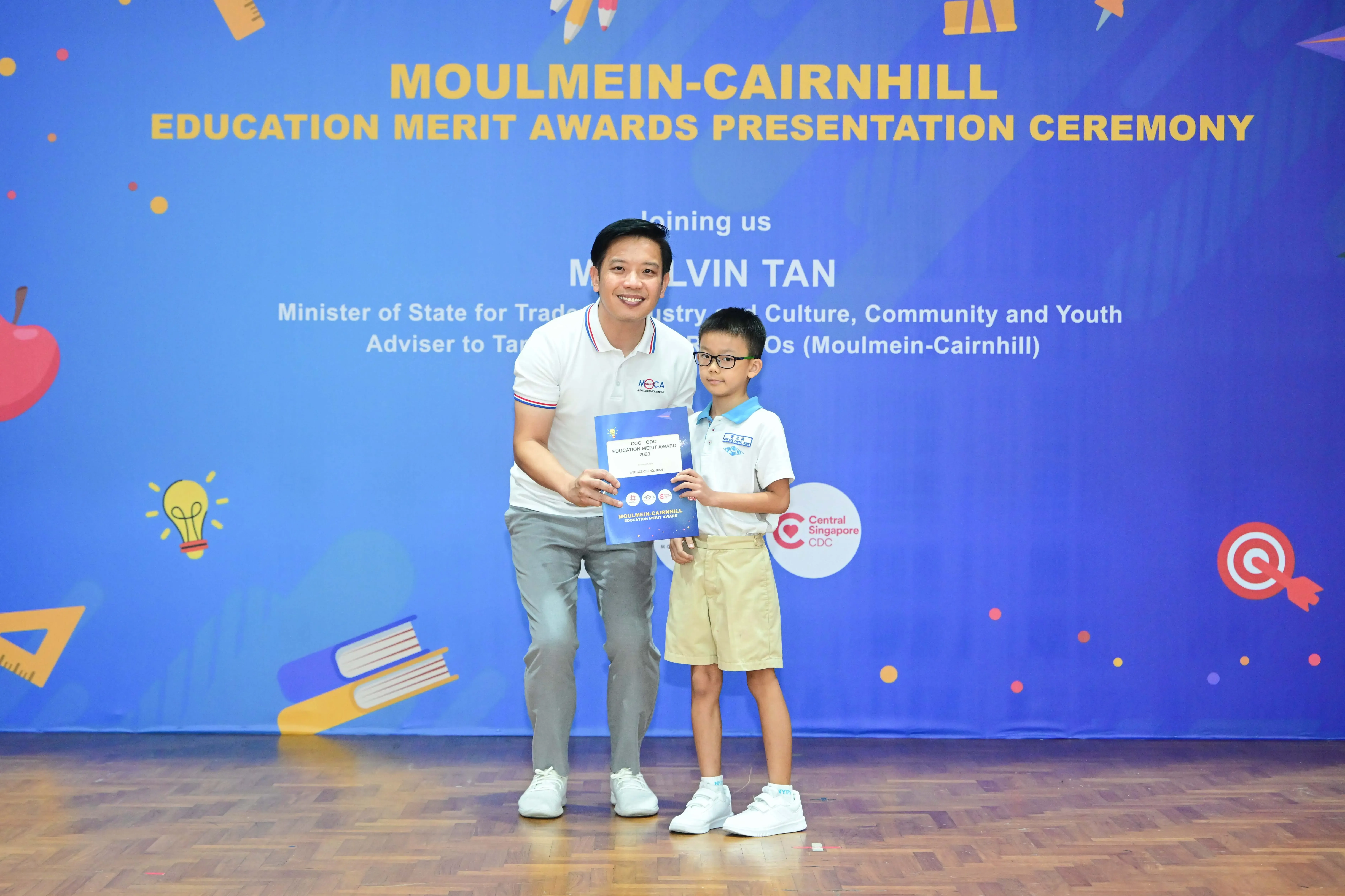Man and young boy holding an award certificate at Moulmein-Cairnhill Education Merit Awards Presentation Ceremony.