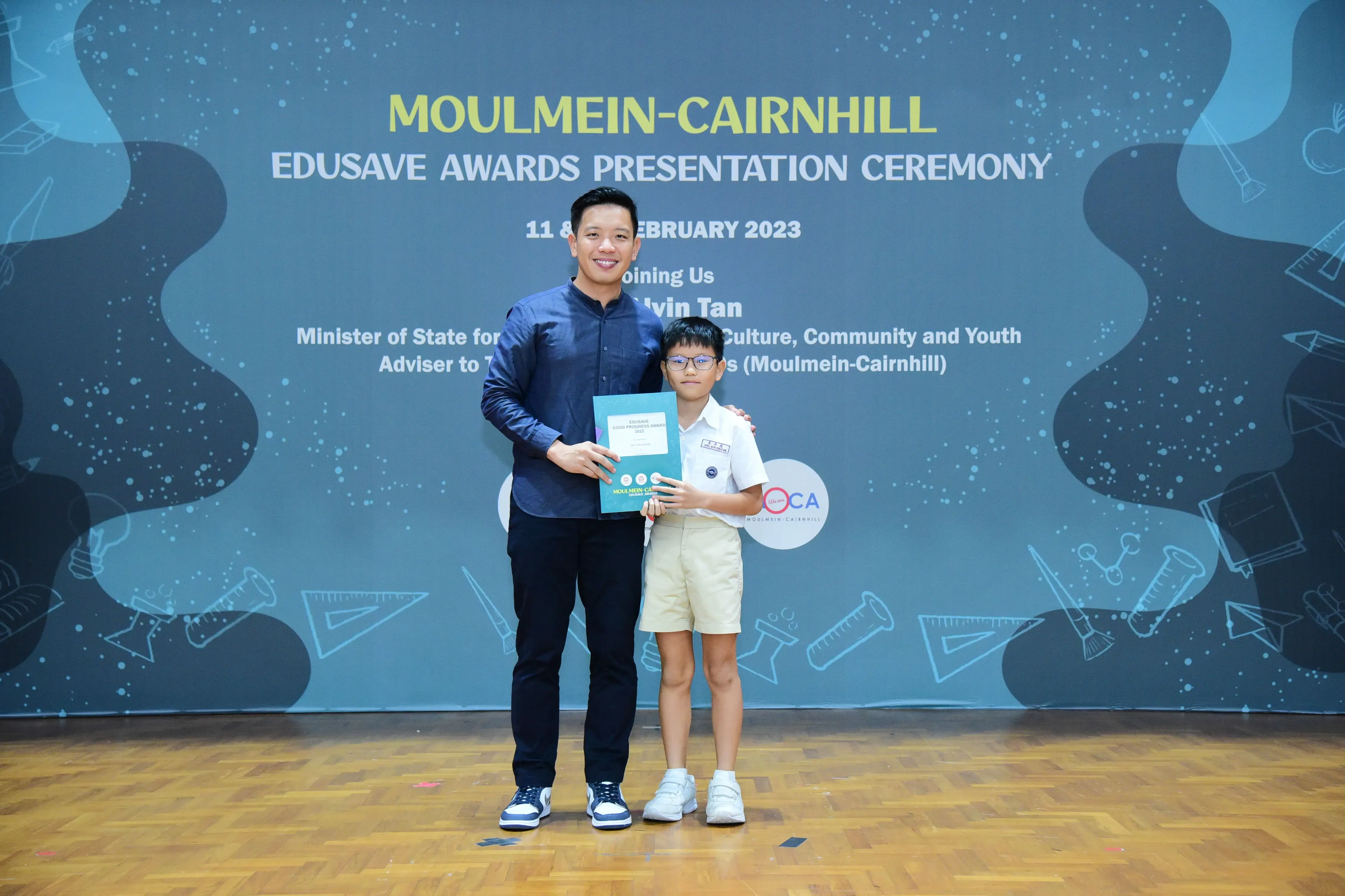 A man and a young boy hold a certificate at the Moulmein-Cairnhill Edusave Awards Presentation Ceremony 2023.