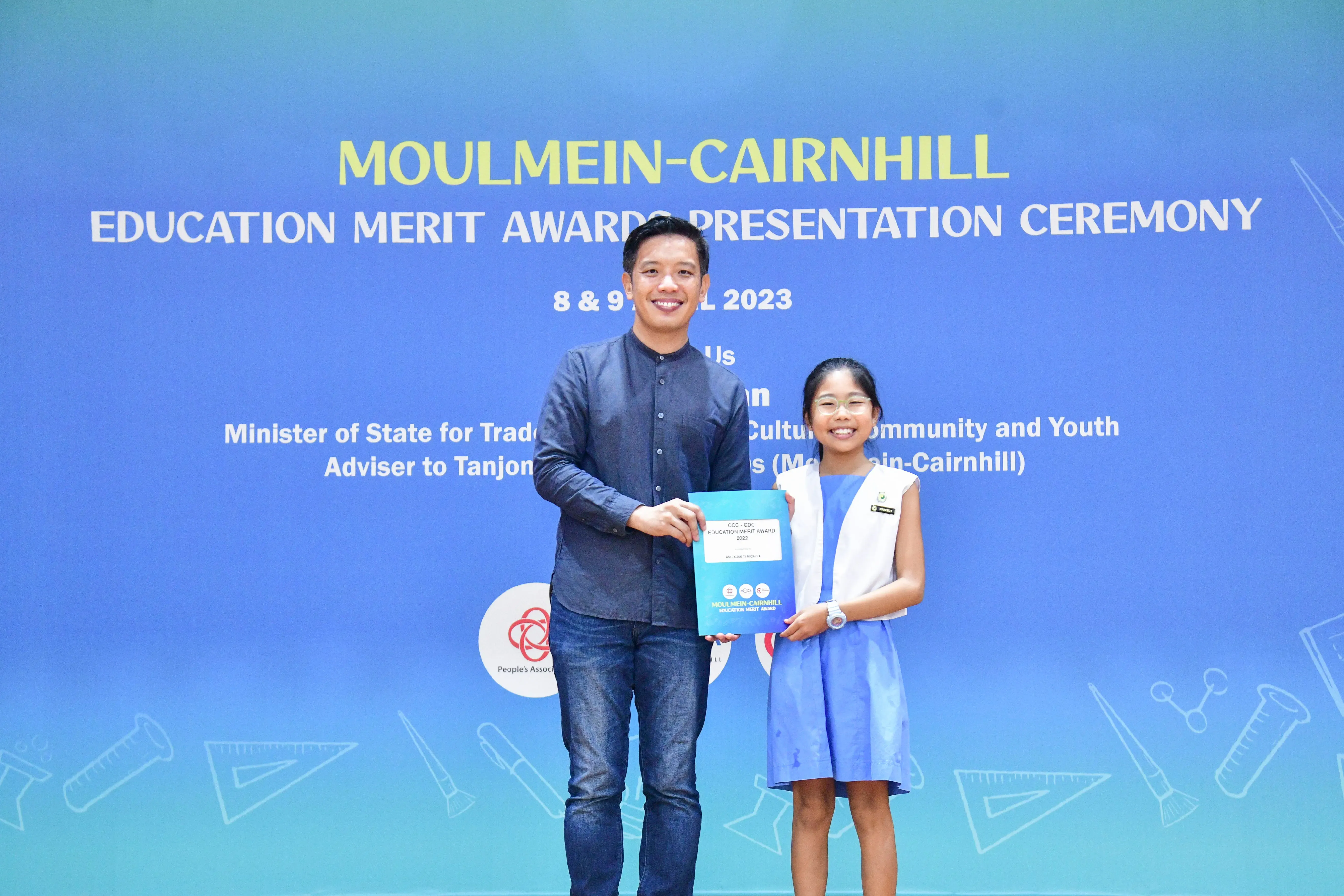 A man and a young girl hold an award certificate together at the Moulmein-Cairnhill Education Merit Awards 2023.