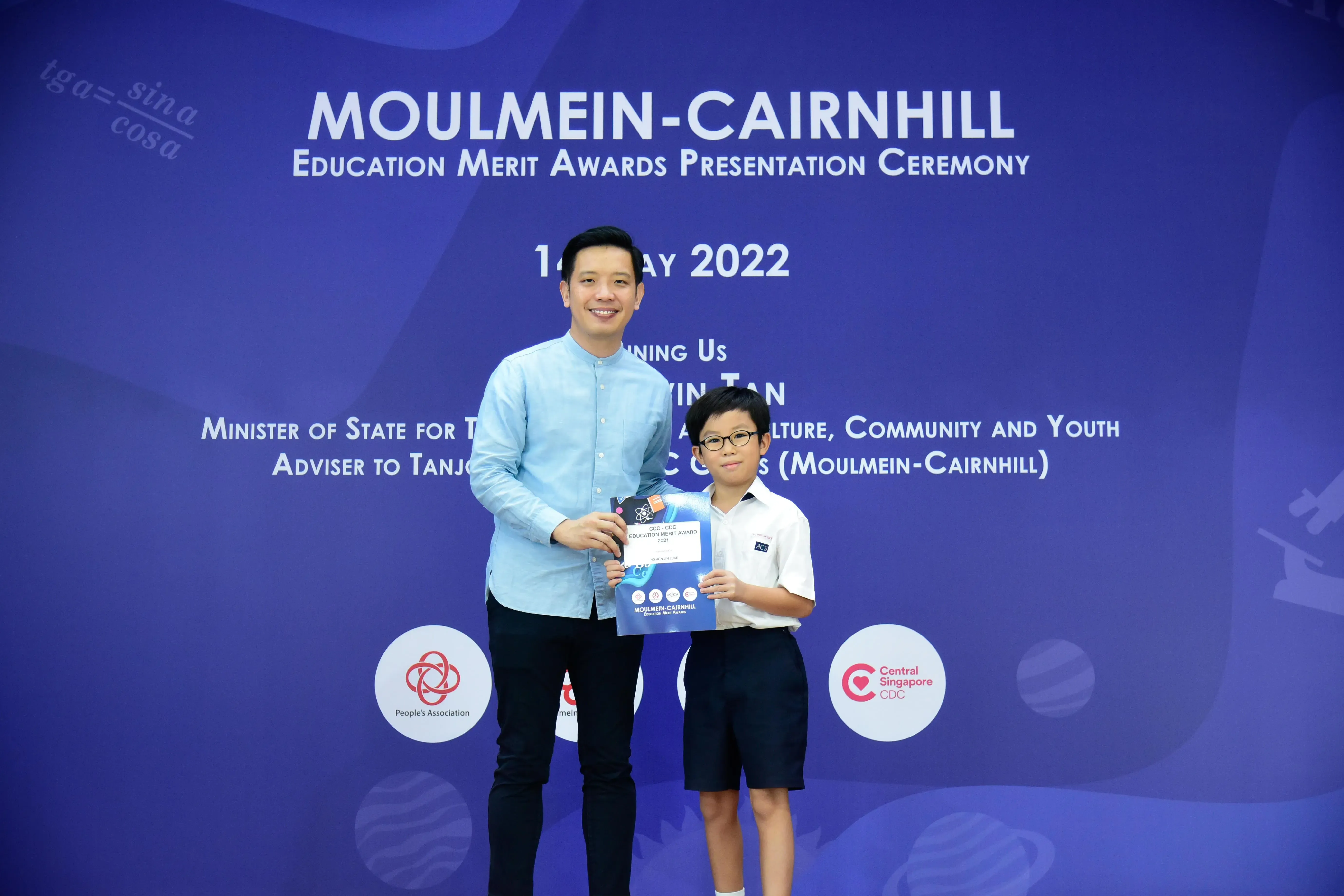 A man and a young boy hold an award certificate at the Moulmein-Cairnhill Education Merit Awards Ceremony 2022.