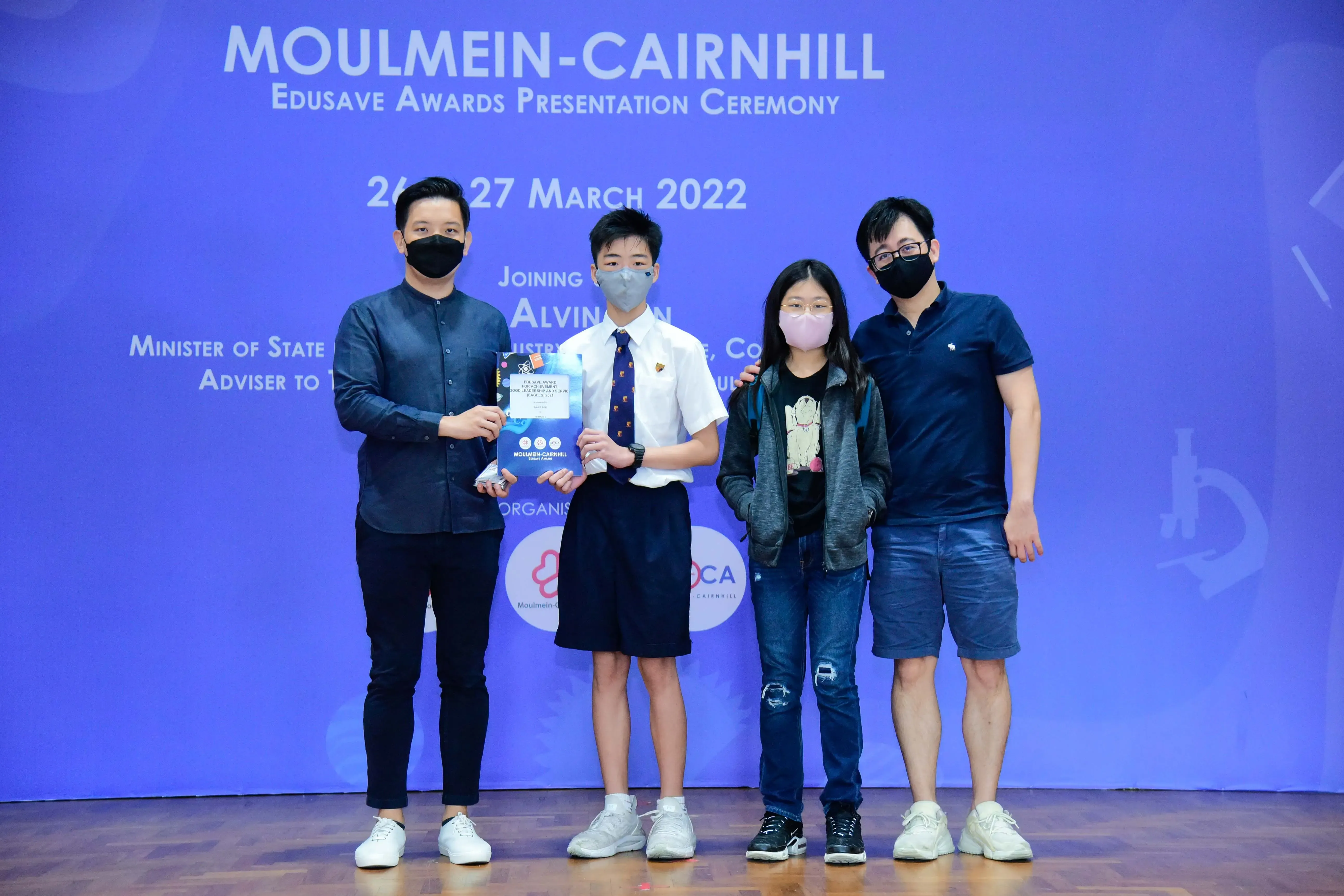 Four masked people pose at the Moulmein-Cairnhill Edusave Awards Presentation Ceremony on 26-27 March 2022.