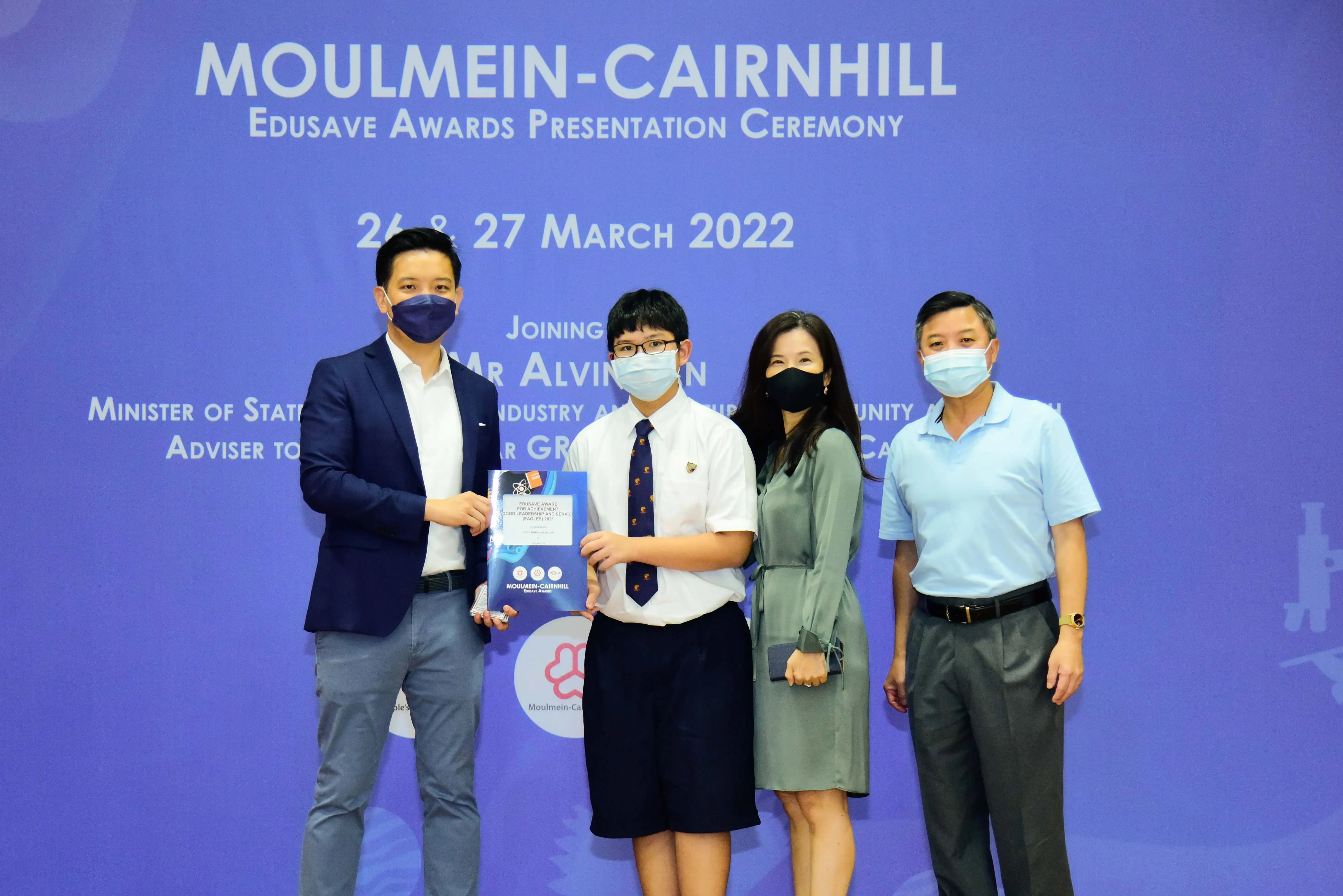 Four masked people pose at the Moulmein-Cairnhill Edusave Awards Presentation Ceremony on 26-27 March 2022.