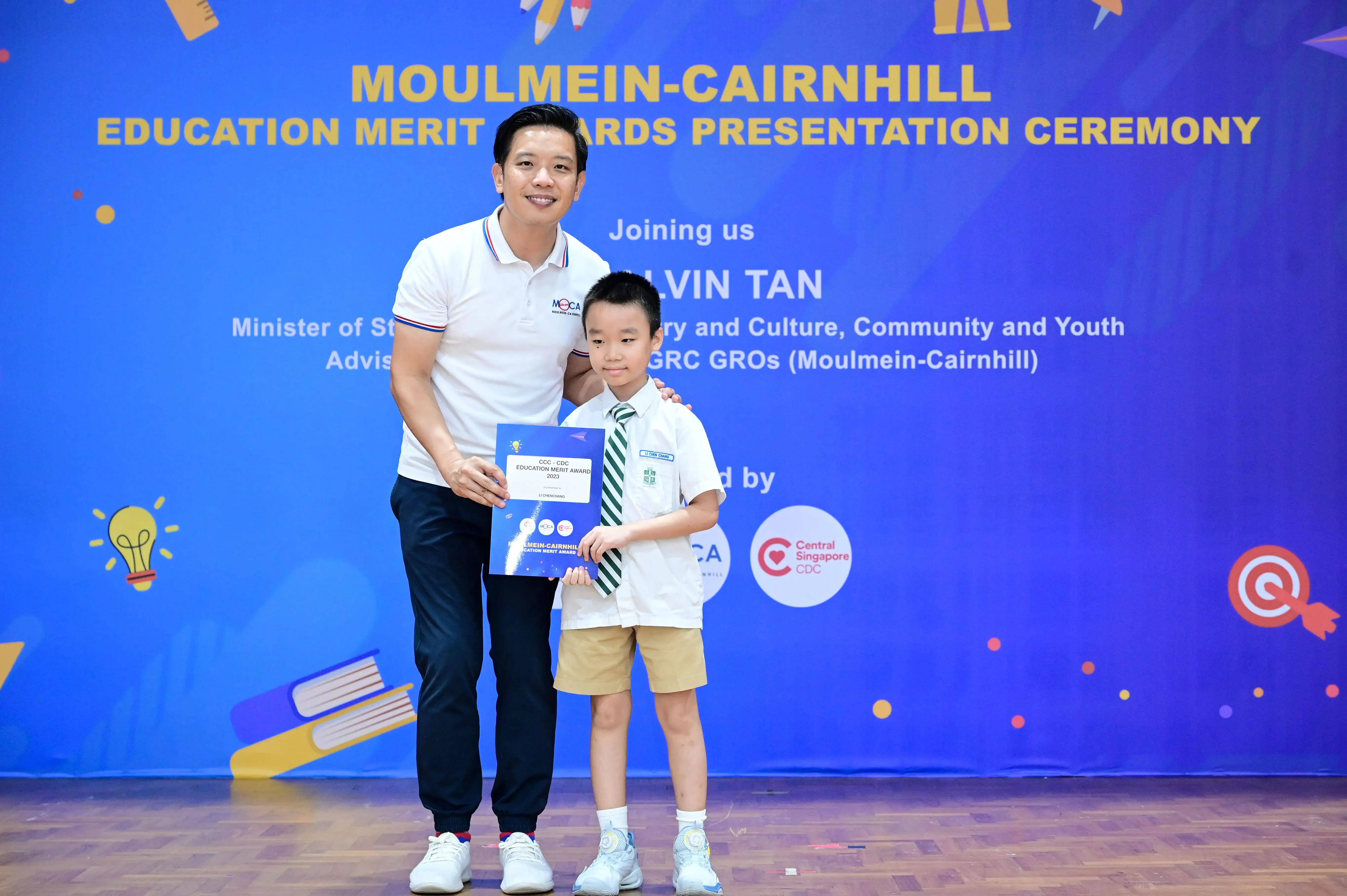 A man and a young boy pose together holding a certificate at the Moulmein-Cairnhill Education Merit Awards Ceremony.