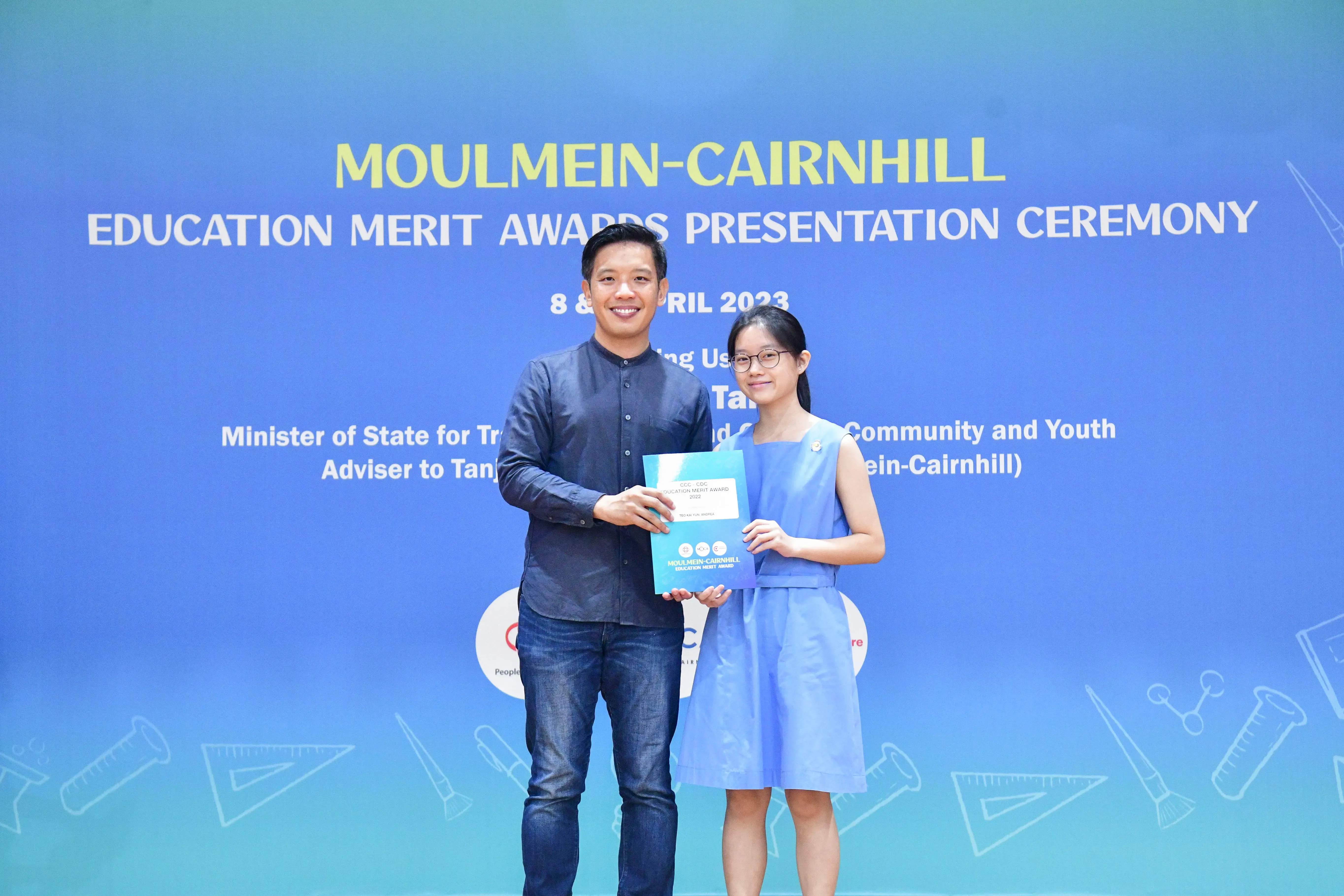 A man and a young girl hold an award certificate together at the Moulmein-Cairnhill Education Merit Awards Ceremony 2023.