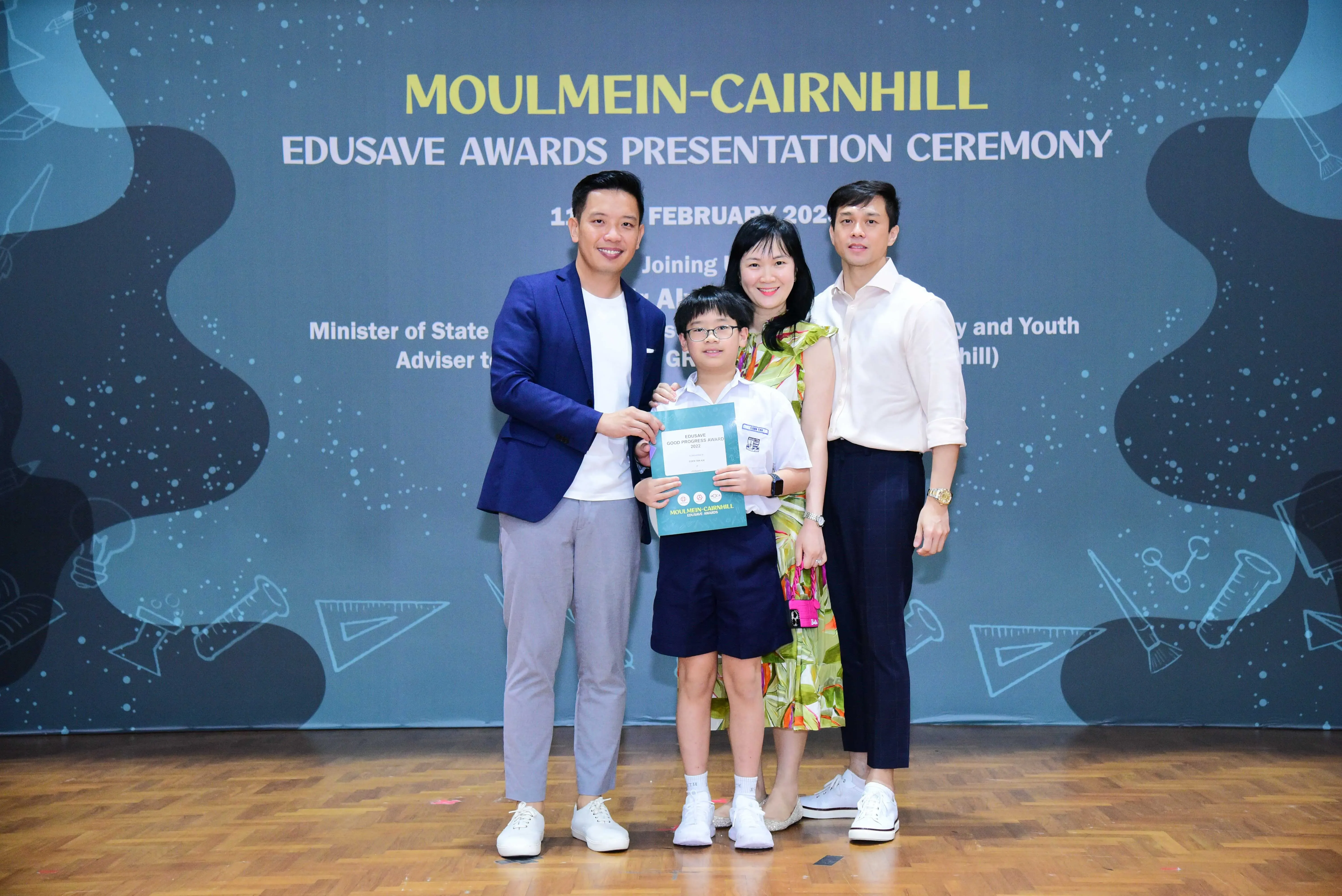 Three adults and a young student holding a certificate pose at the Moulmein-Cairnhill Edusave Awards Presentation Ceremony.
