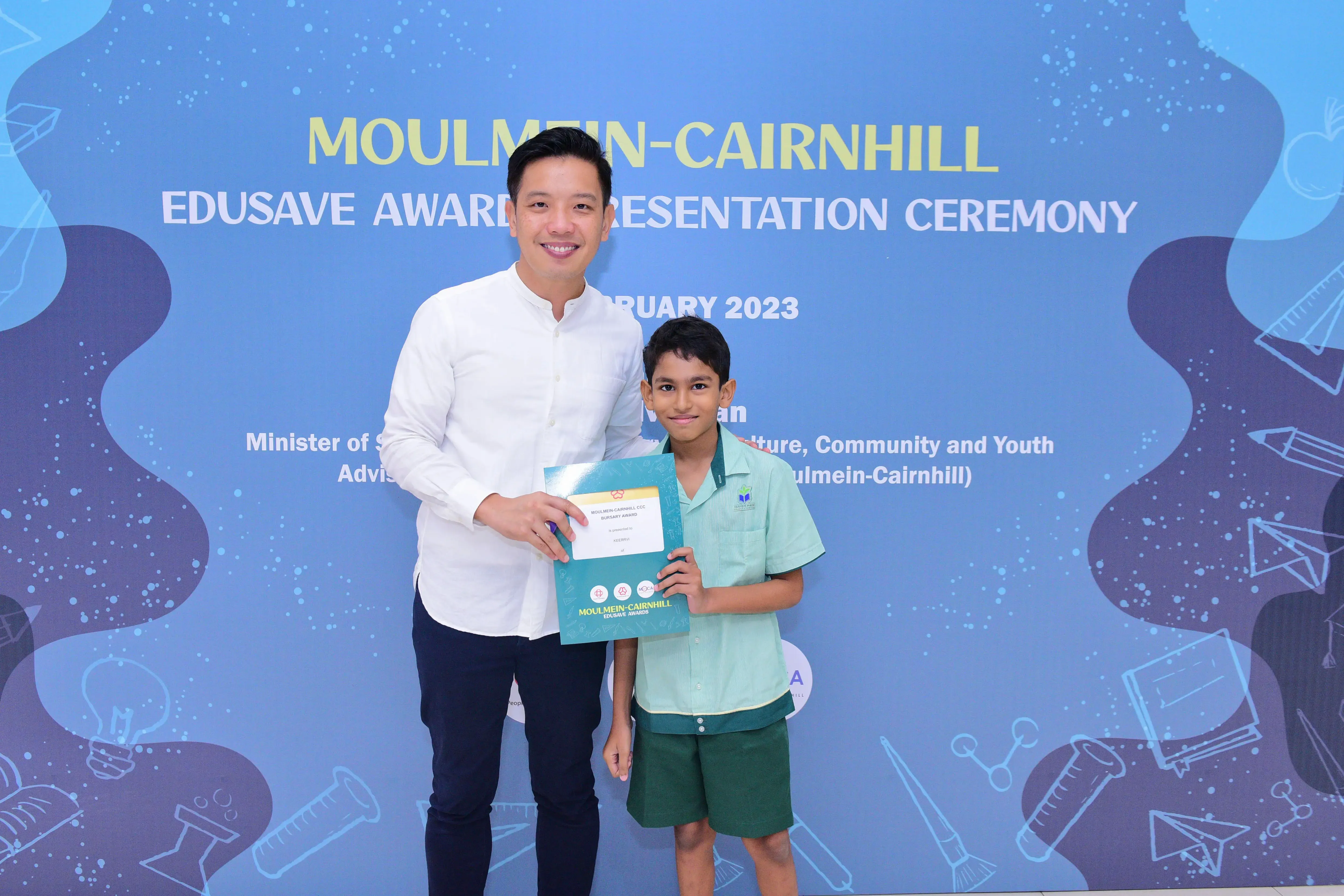 A man and a young boy hold a certificate together at the Moulmein-Cairnhill Edusave Awards Ceremony in 2023.