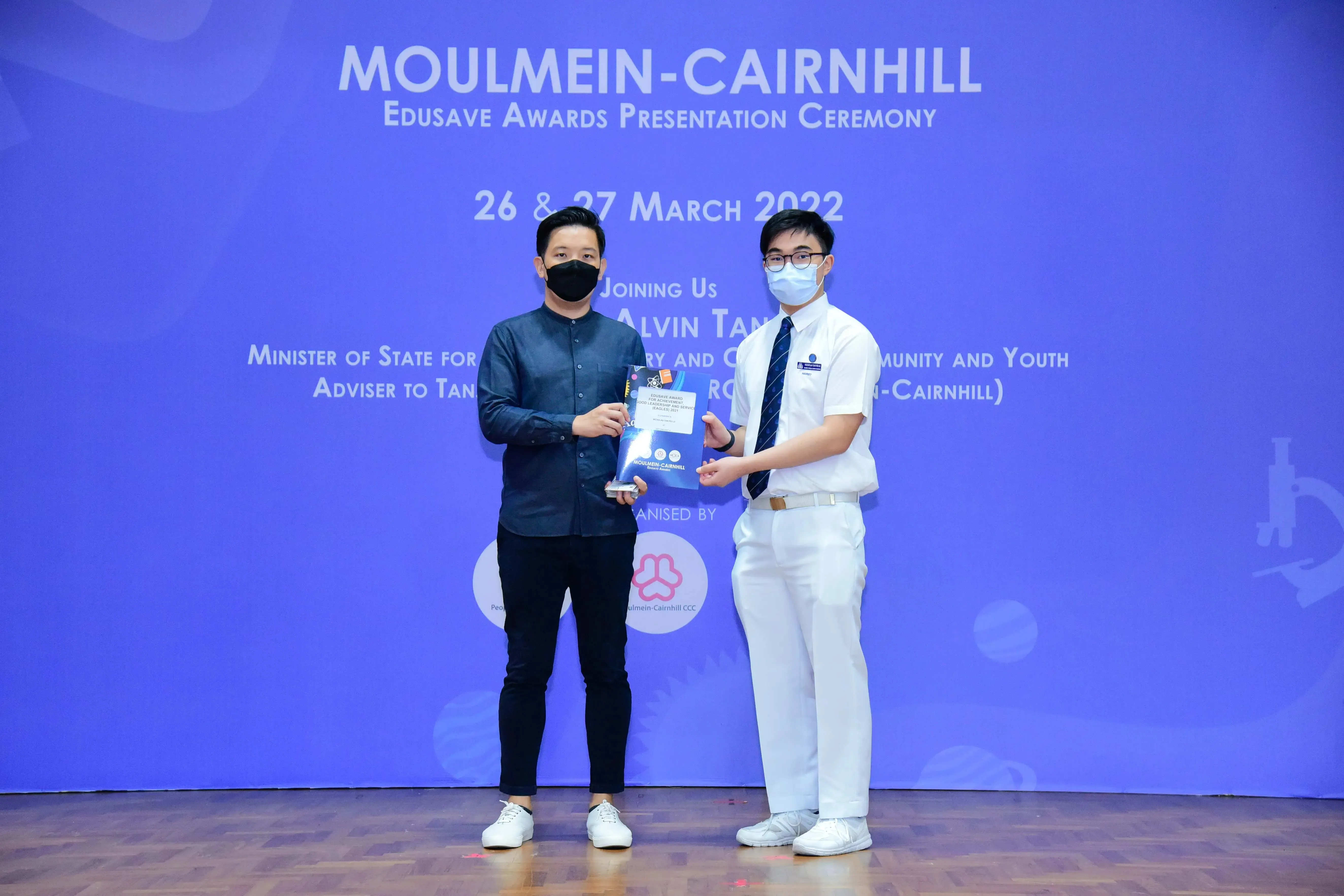 Two masked men holding an award at the Moulmein-Cairnhill Edusave Awards Ceremony on March 26-27, 2022.