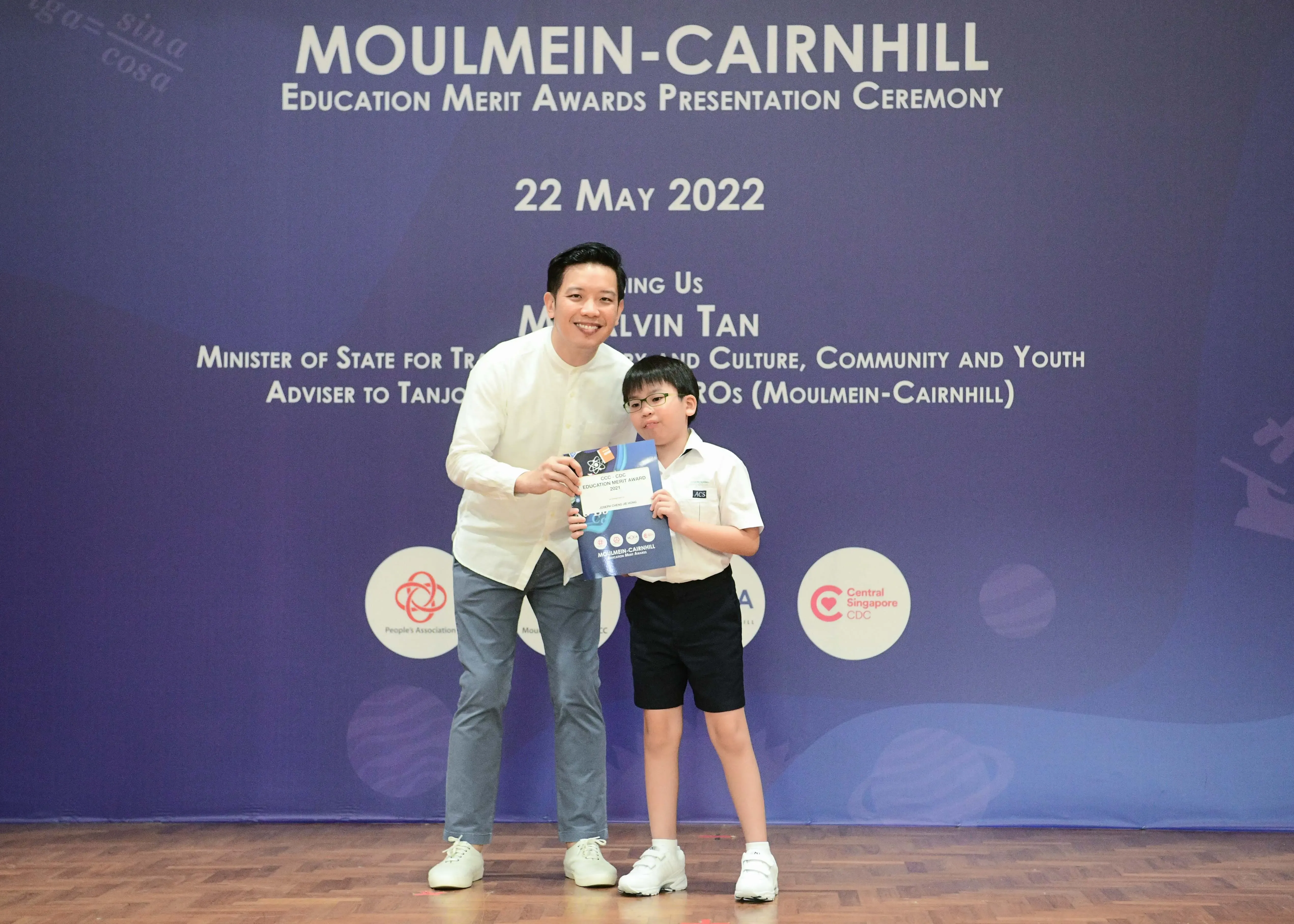 A man and a young boy hold an award booklet at the Moulmein-Cairnhill Education Merit Awards on 22 May 2022.