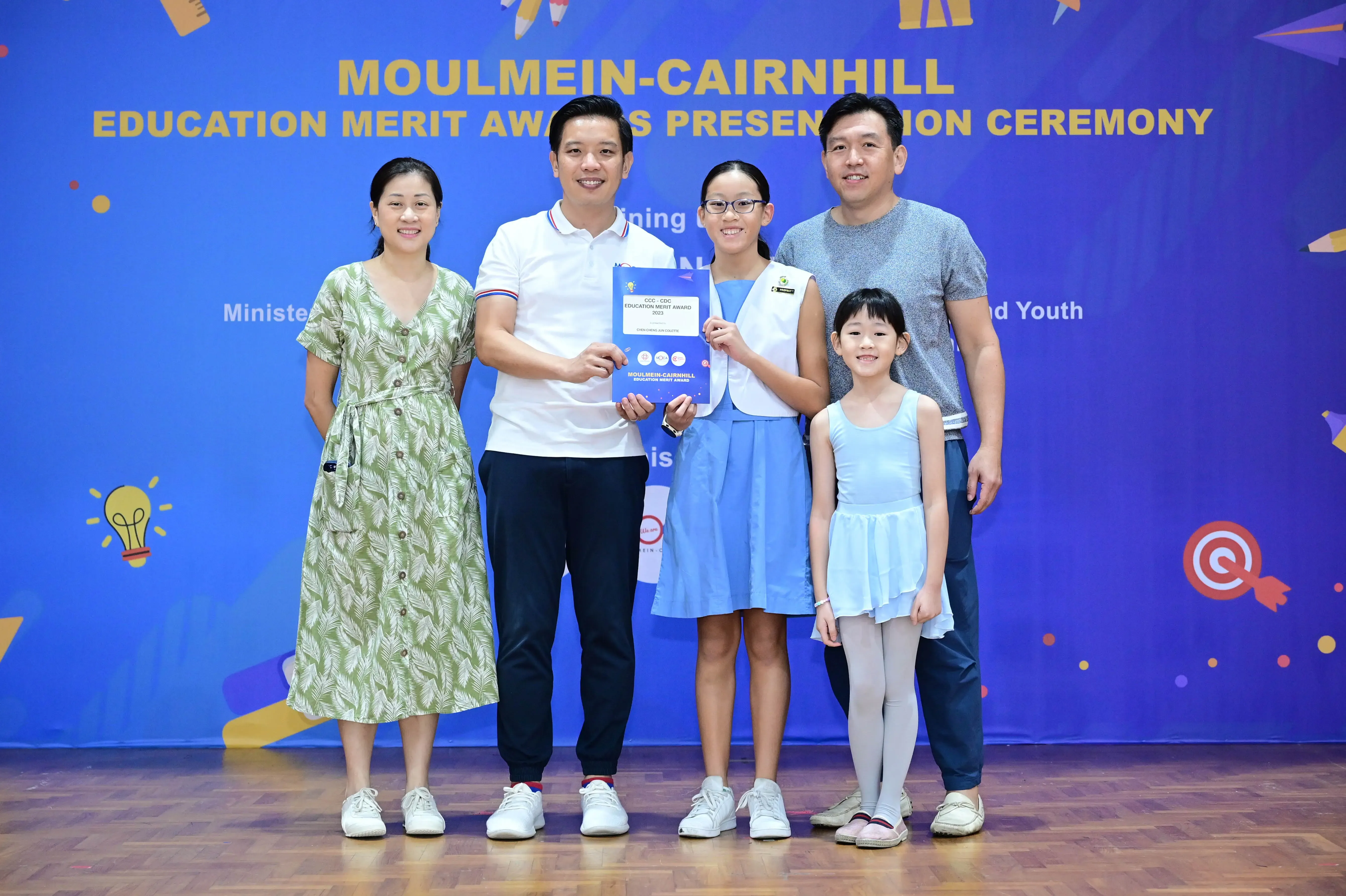 Five people pose with an award certificate at the Moulmein-Cairnhill Education Merit Awards Presentation Ceremony.
