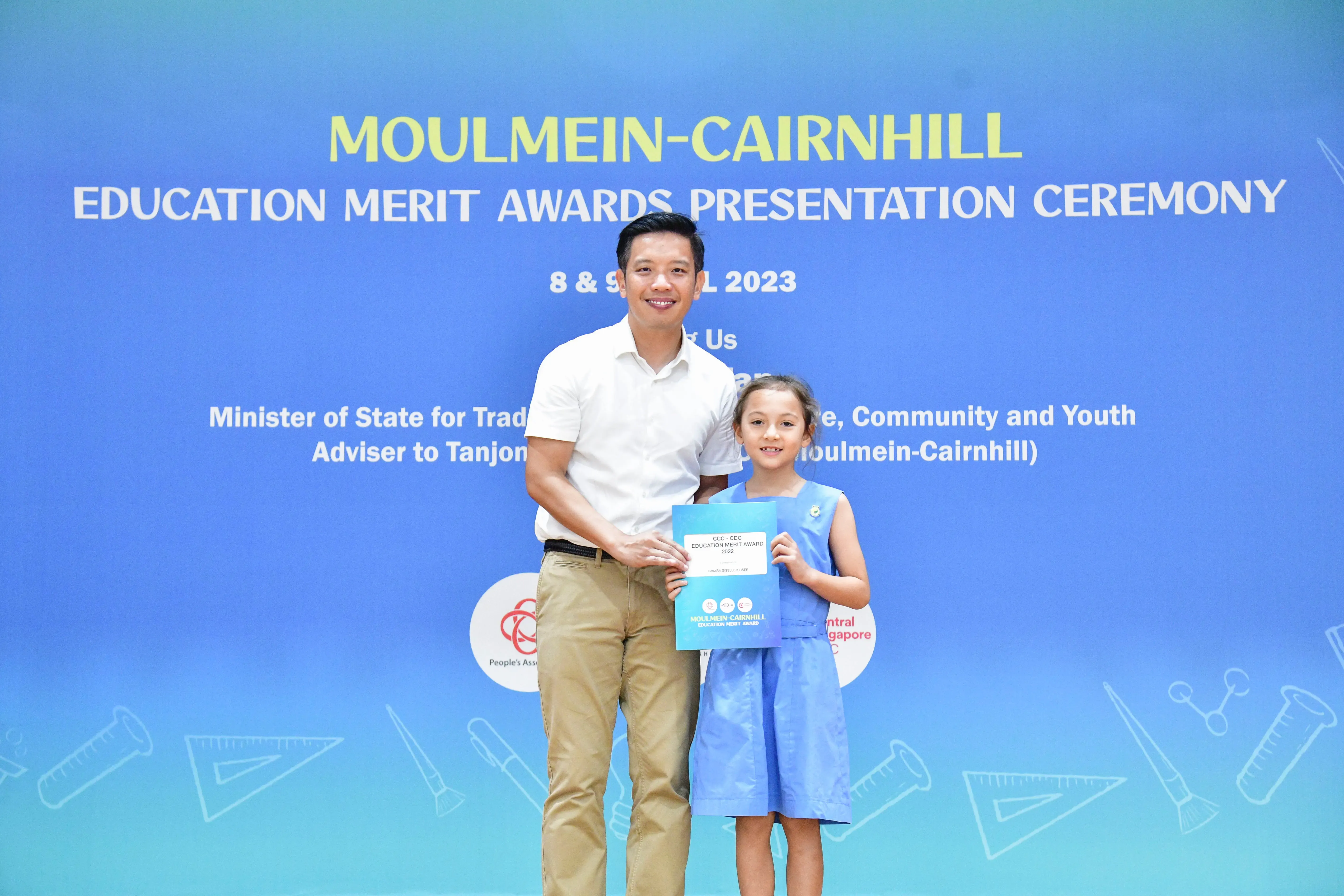 A man and a young girl holding an award certificate at the Moulmein-Cairnhill Education Merit Awards Ceremony 2023.