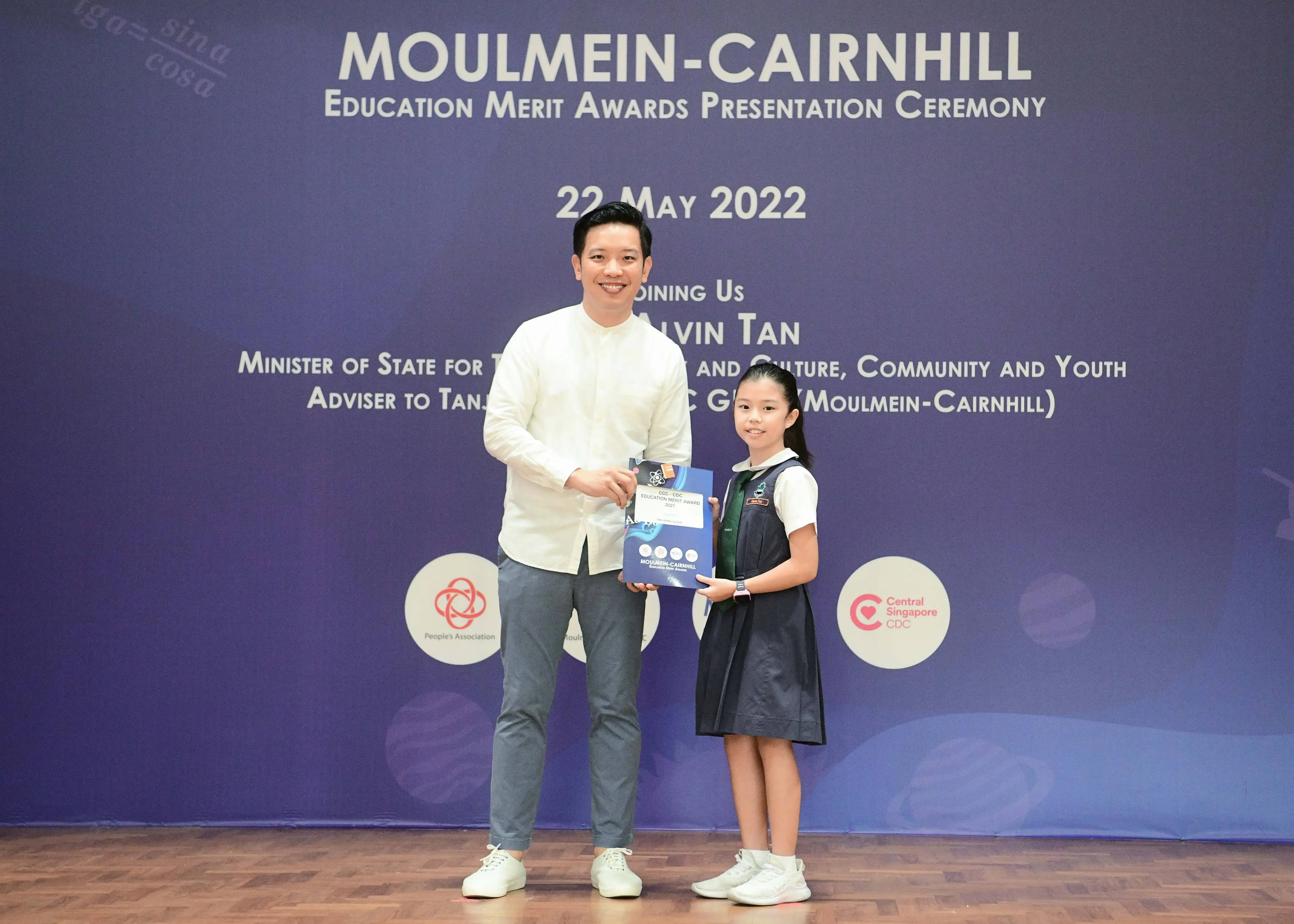 A man and a young girl hold an award together at the Moulmein-Cairnhill Education Merit Awards on 22 May 2022.