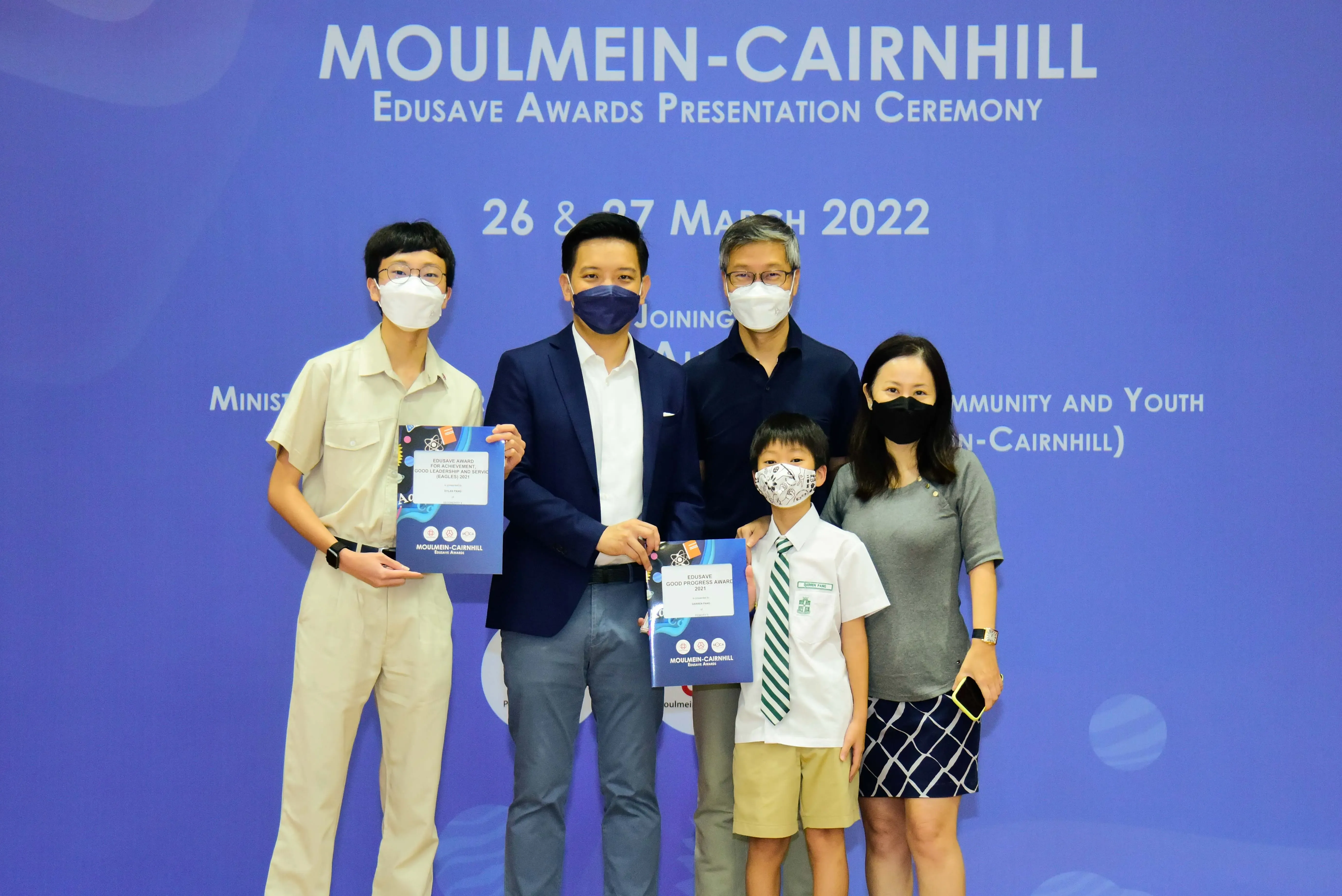 Five masked people pose with award certificates at the Moulmein-Cairnhill Edusave Awards Ceremony, March 2022.