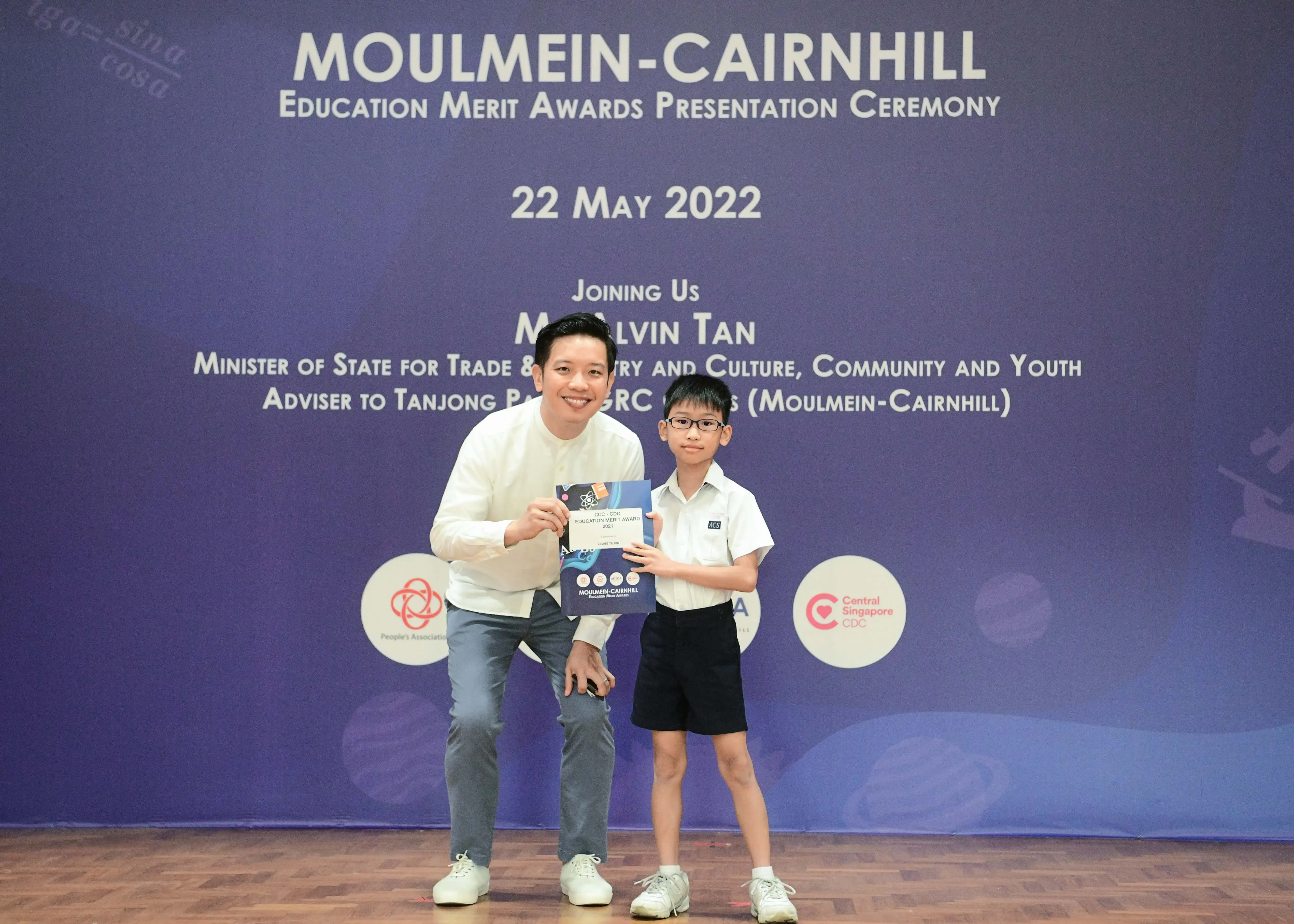 A man and a young boy holding an award certificate at the Moulmein-Cairnhill Education Merit Awards on 22 May 2022.
