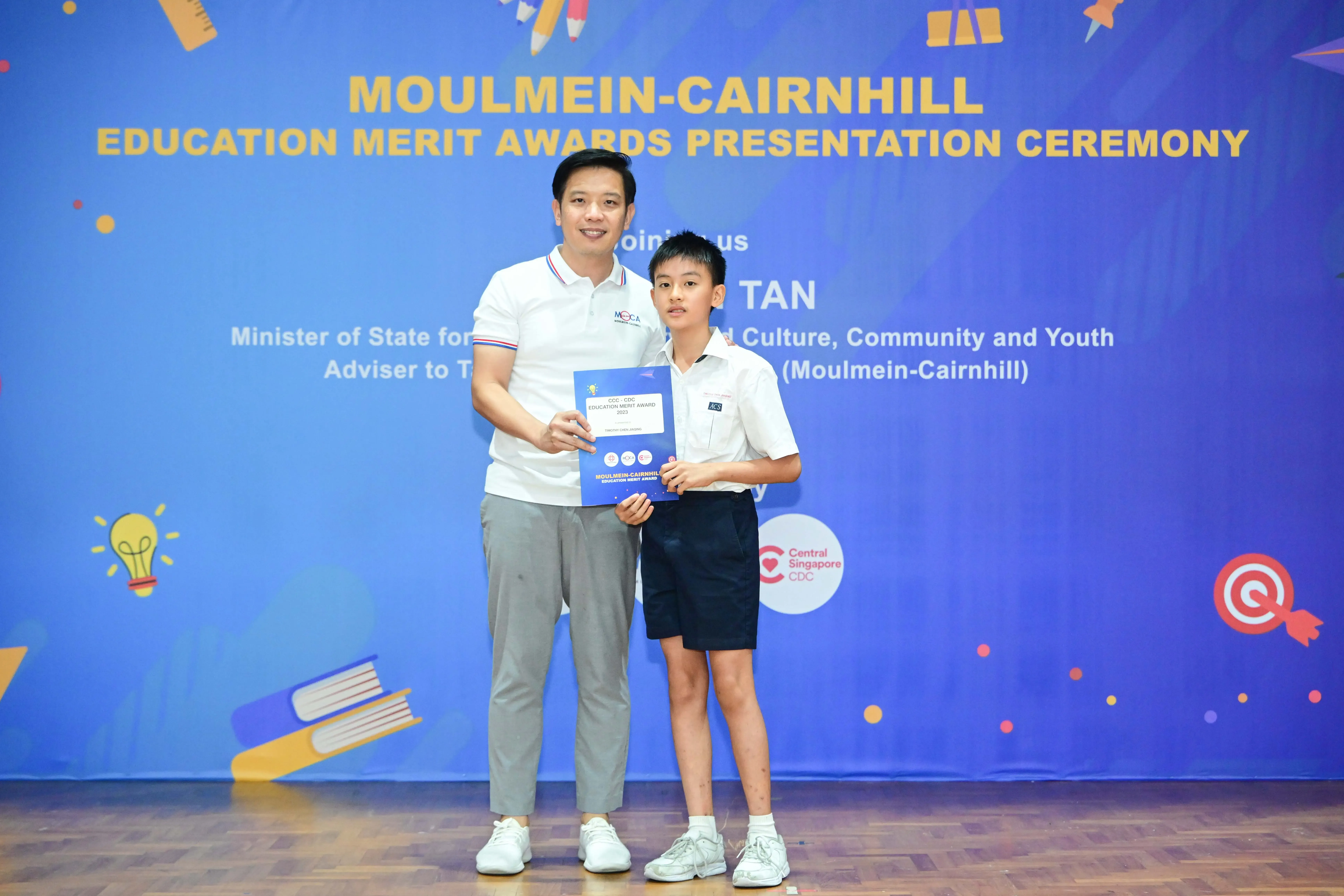 Man and young boy holding a certificate at Moulmein-Cairnhill Education Merit Awards Presentation Ceremony.