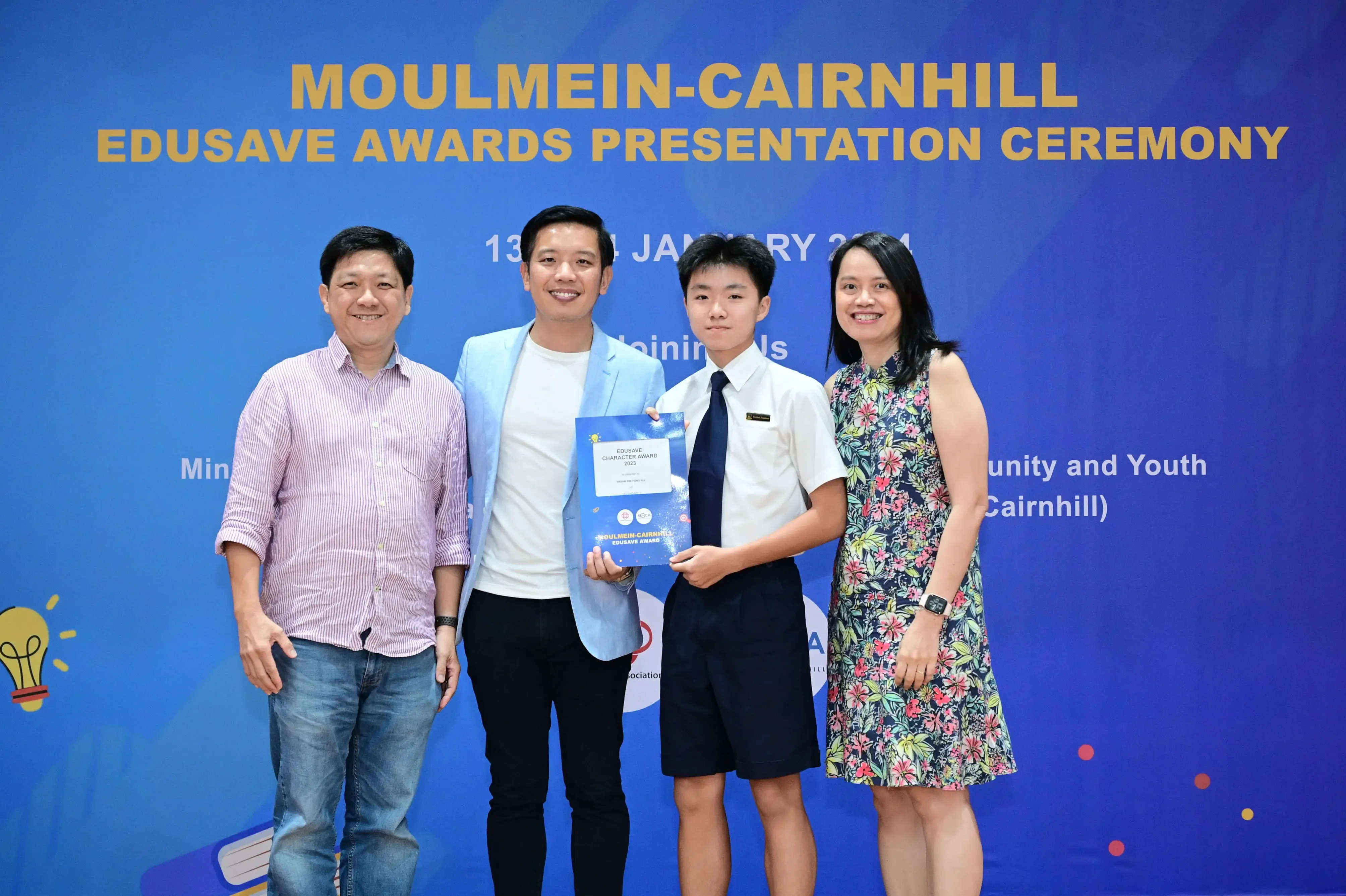 Four people pose at the Moulmein-Cairnhill Edusave Awards Presentation Ceremony, with a student holding an award.