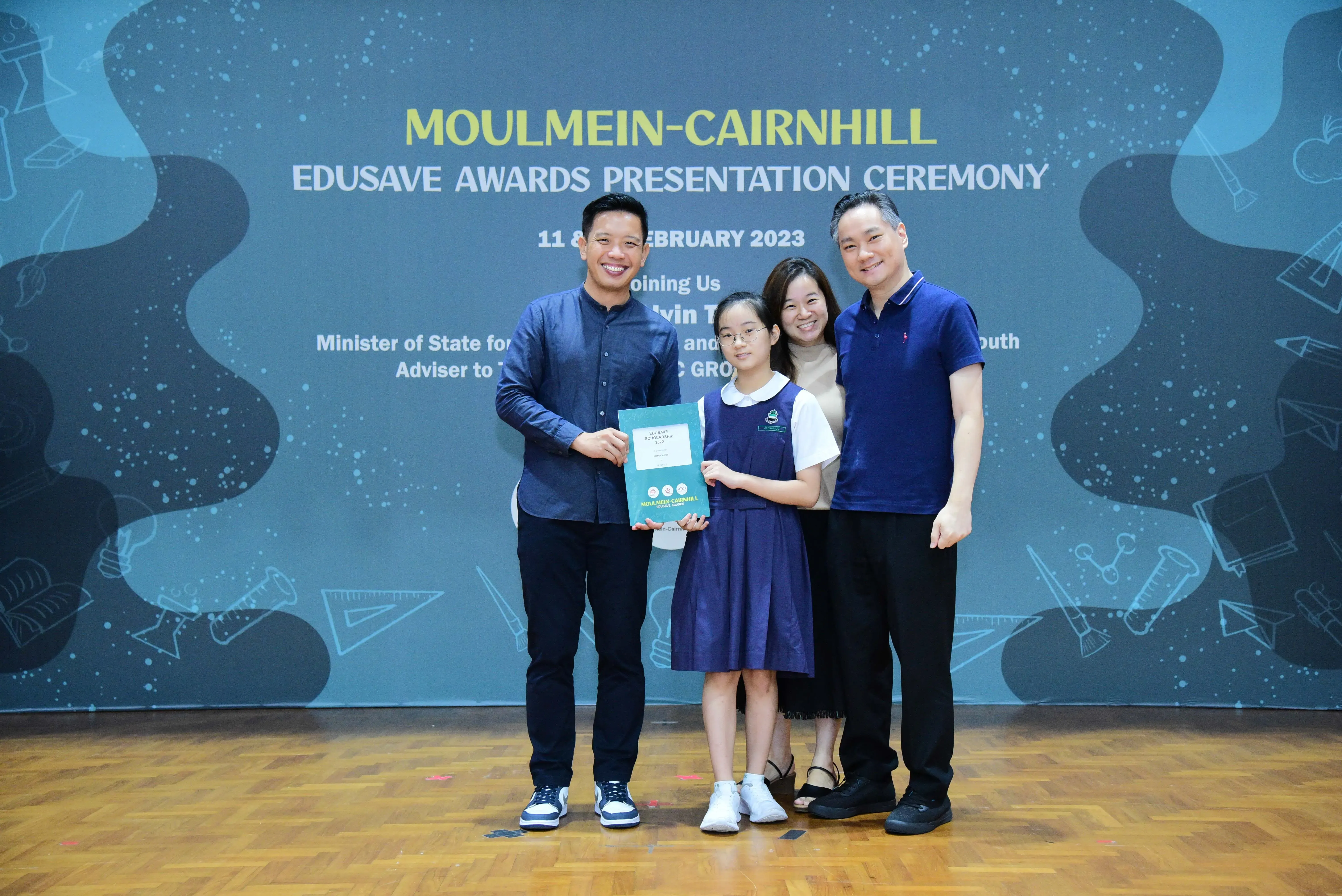 Four people pose with a certificate at the Moulmein-Cairnhill Edusave Awards Presentation Ceremony, February 2023.