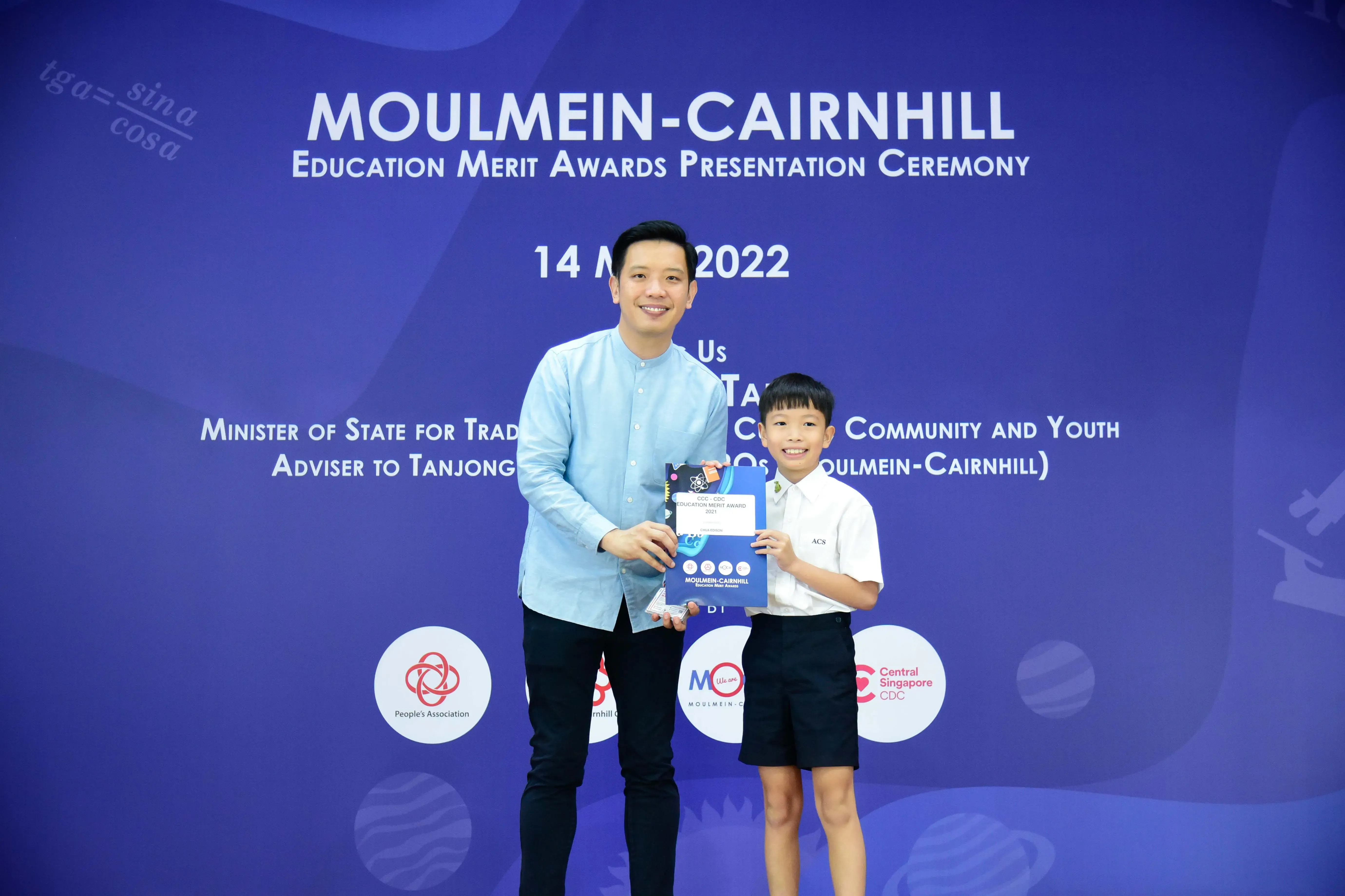 A man and a young boy hold an award certificate at the Moulmein-Cairnhill Education Merit Awards Ceremony 2022.