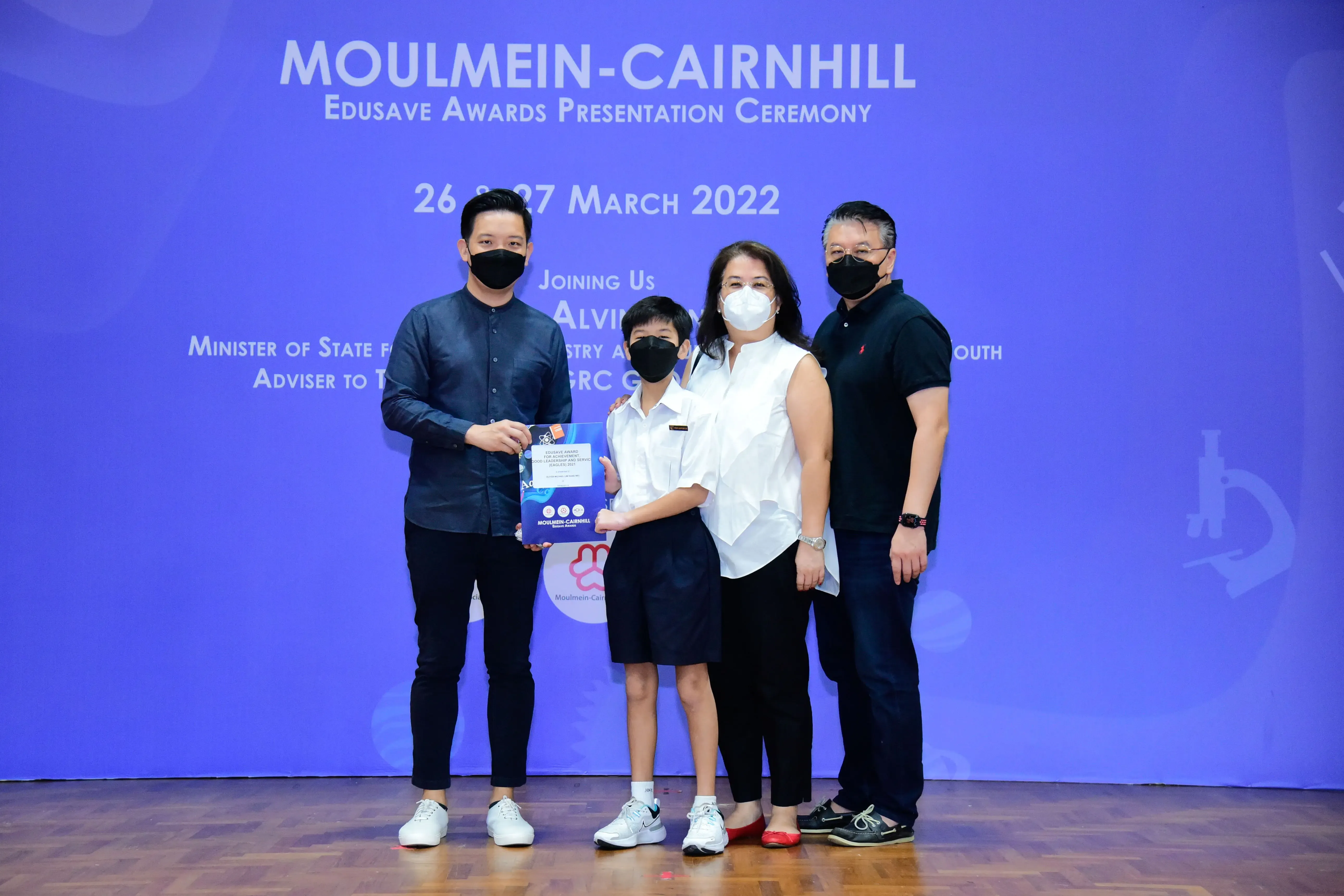 Four masked people pose at the Moulmein-Cairnhill Edusave Awards Presentation Ceremony on 26-27 March 2022.