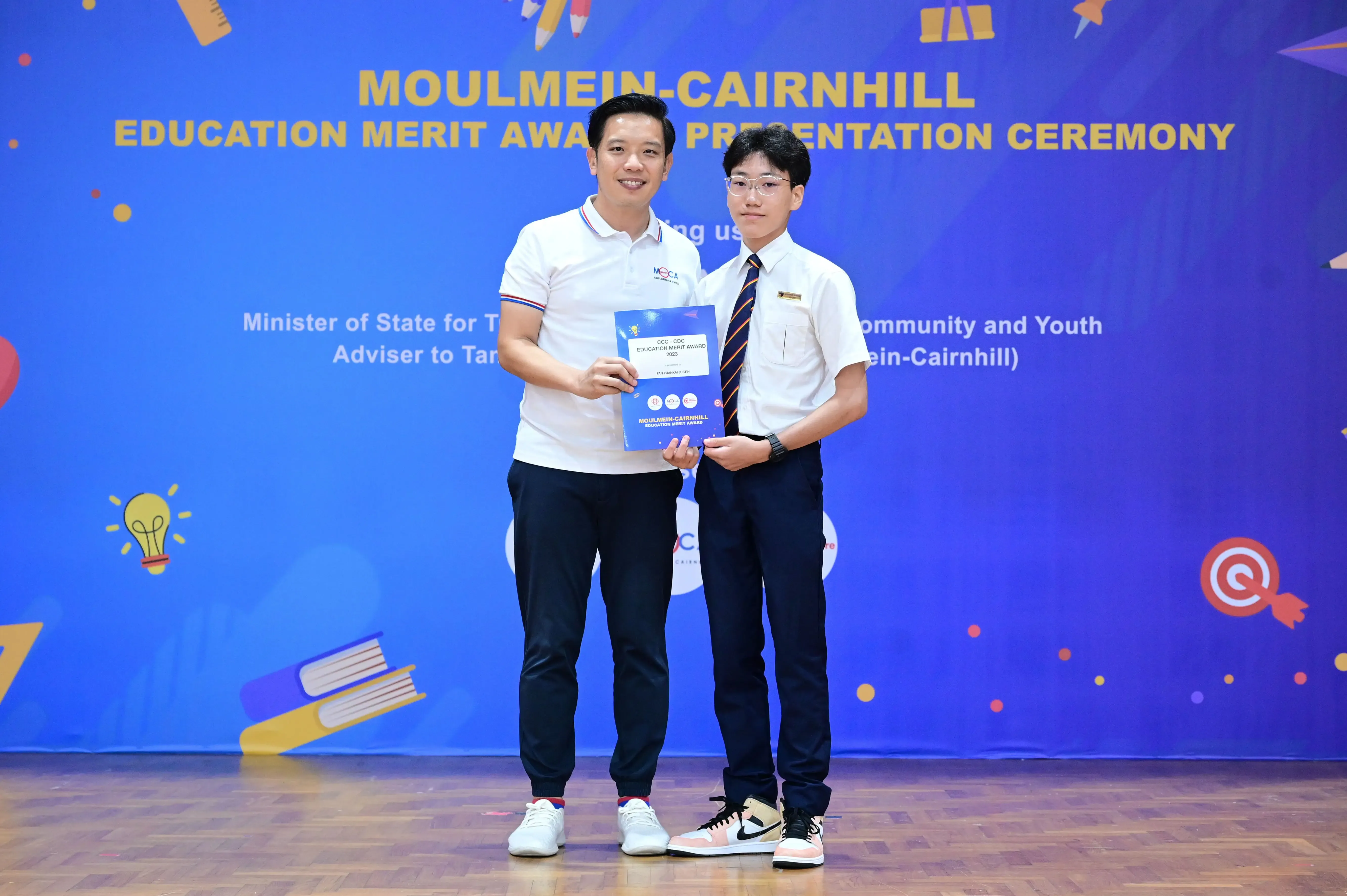 Two men hold an award certificate at the Moulmein-Cairnhill Education Merit Award Presentation Ceremony.
