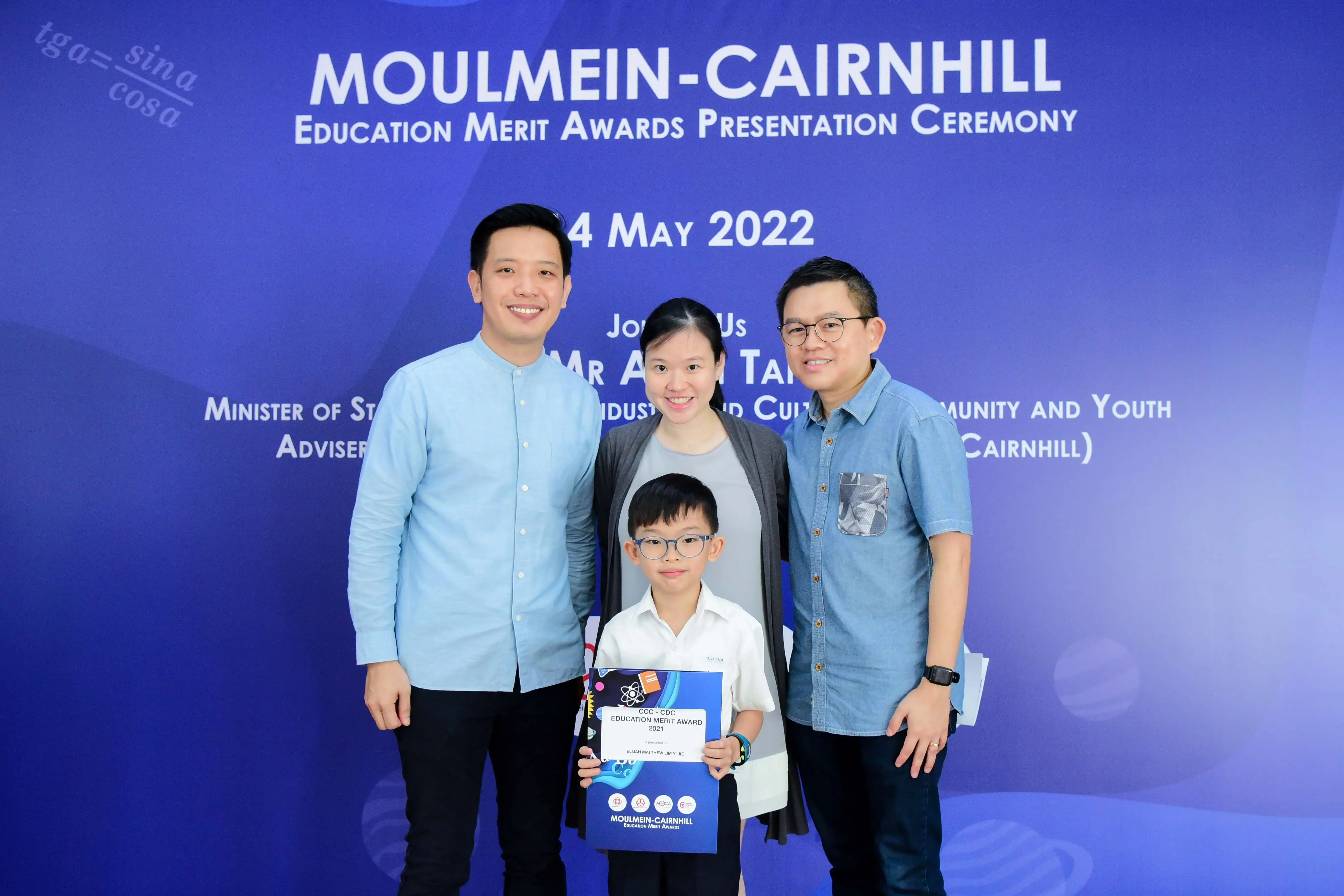 Three adults and a young boy holding an award certificate pose at the Moulmein-Cairnhill Education Merit Awards ceremony, May 2022.
