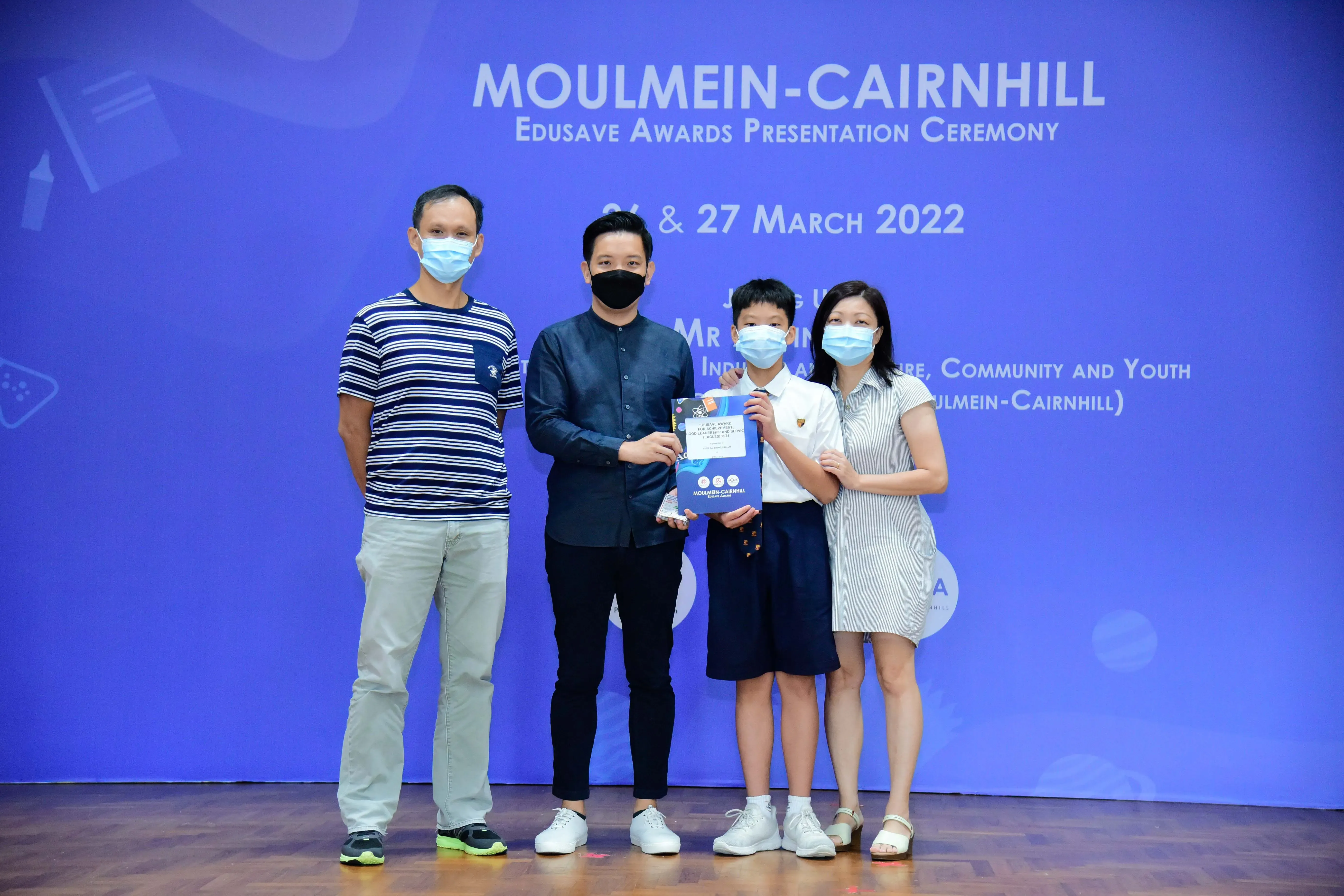 Four masked people pose at the Moulmein-Cairnhill Edusave Awards Presentation Ceremony on 27 March 2022.