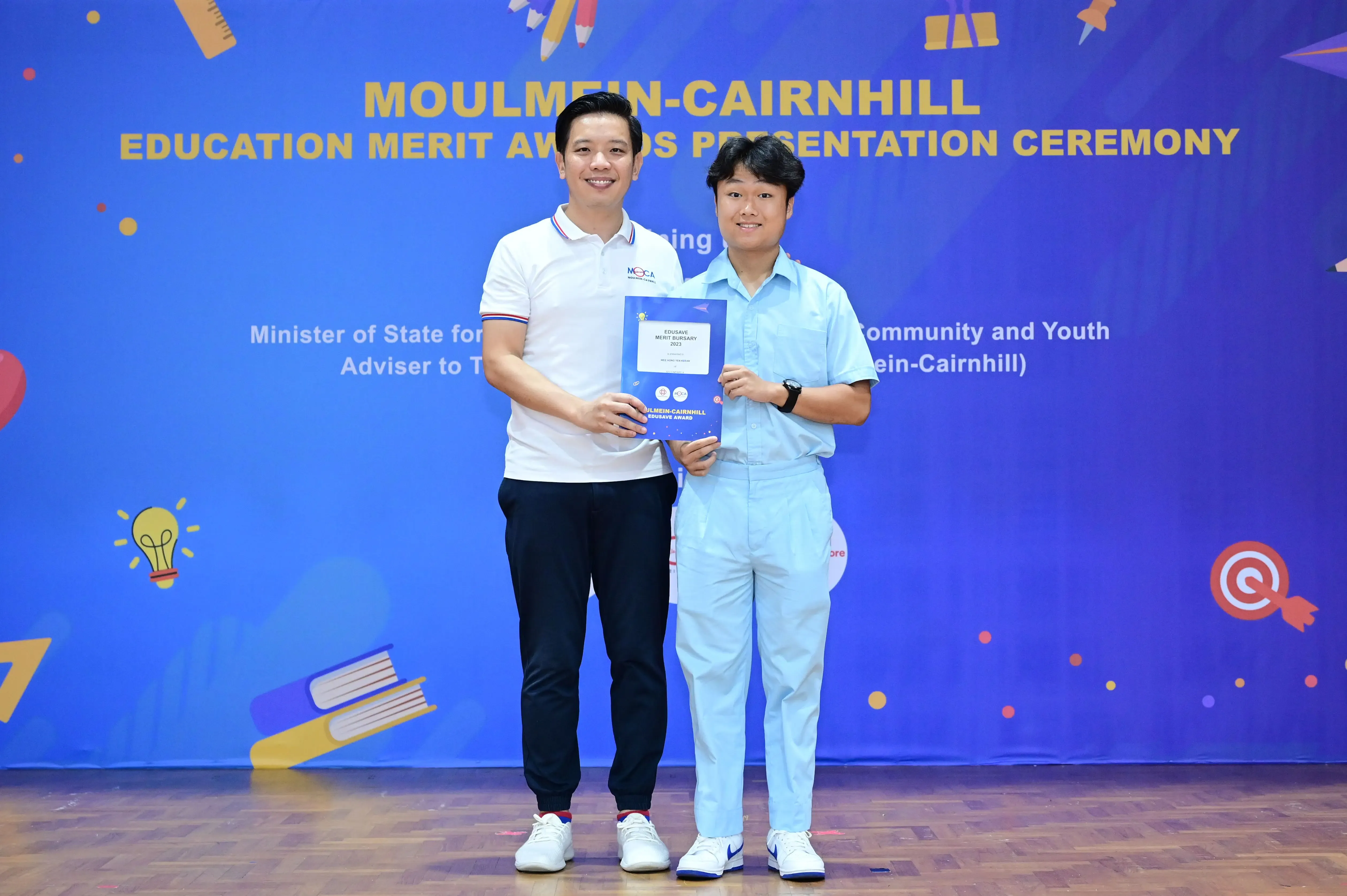 Two men holding a certificate at the Moulmein-Cairnhill Education Merit Awards Presentation Ceremony.