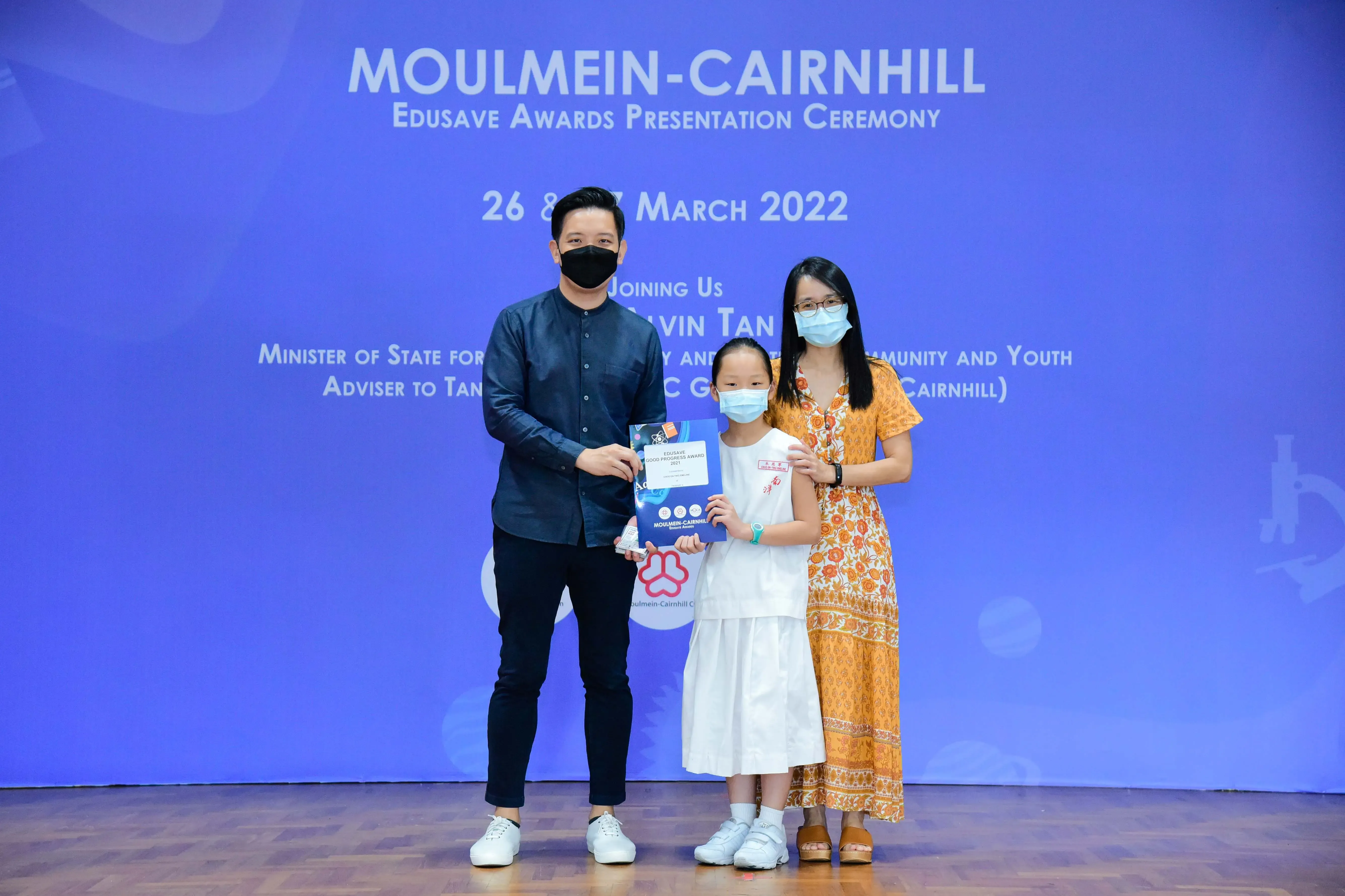 Three masked people pose at the Moulmein-Cairnhill Edusave Awards Presentation Ceremony, March 2022.