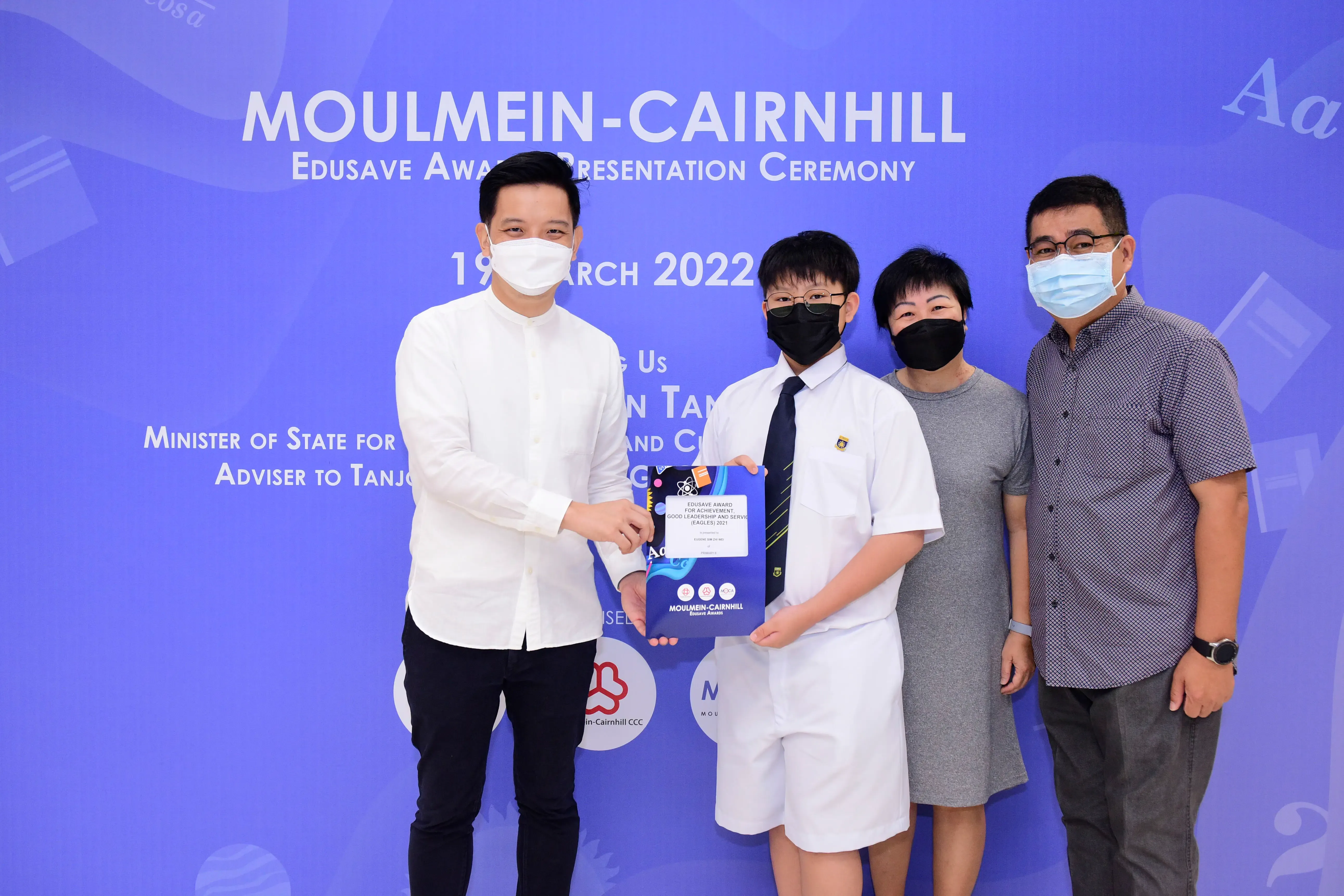 Four masked people pose at the Moulmein-Cairnhill Edusave Award Presentation Ceremony on 19 March 2022.