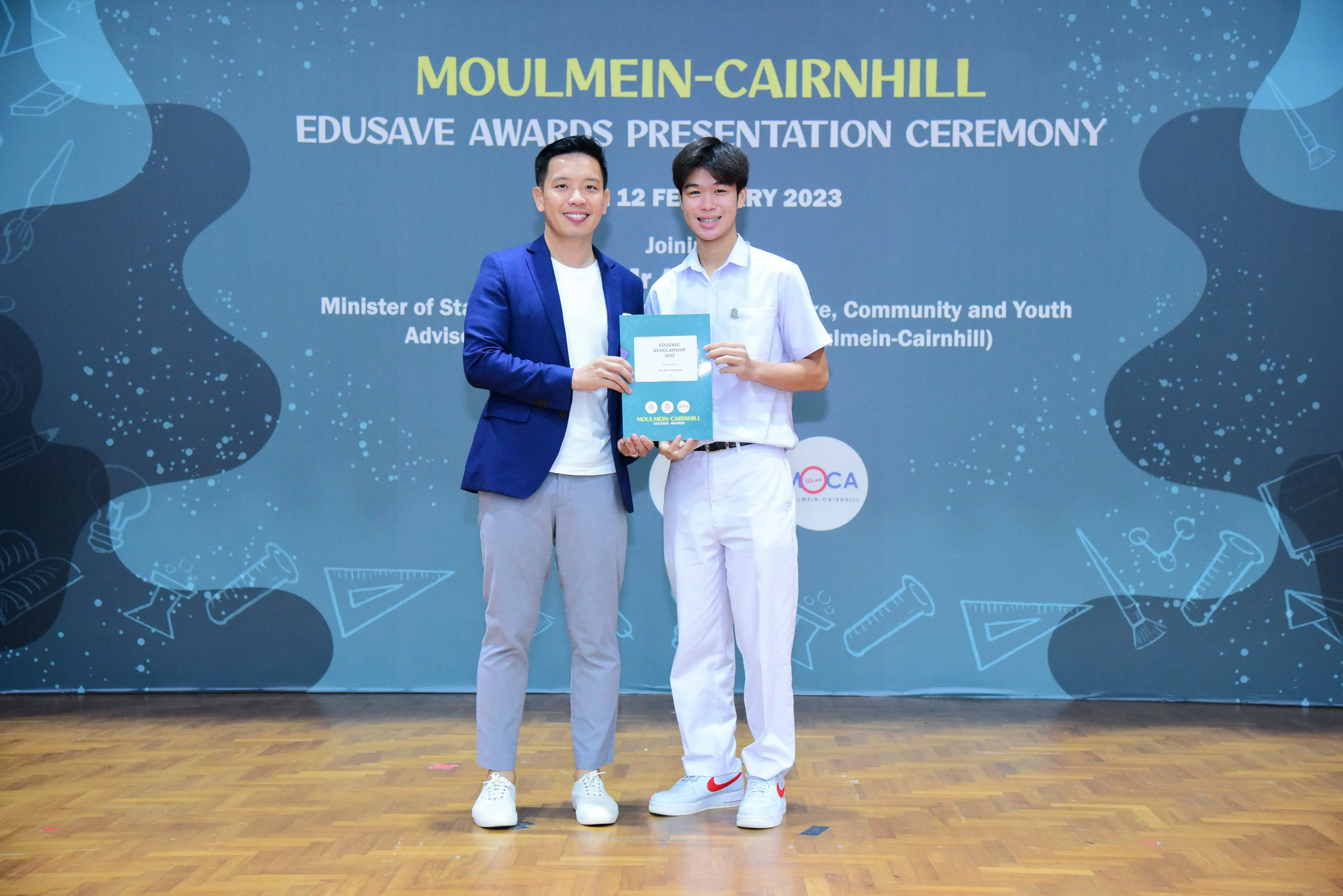Two men hold a certificate at the Moulmein-Cairnhill Edusave Awards Presentation Ceremony on 12 February 2023.