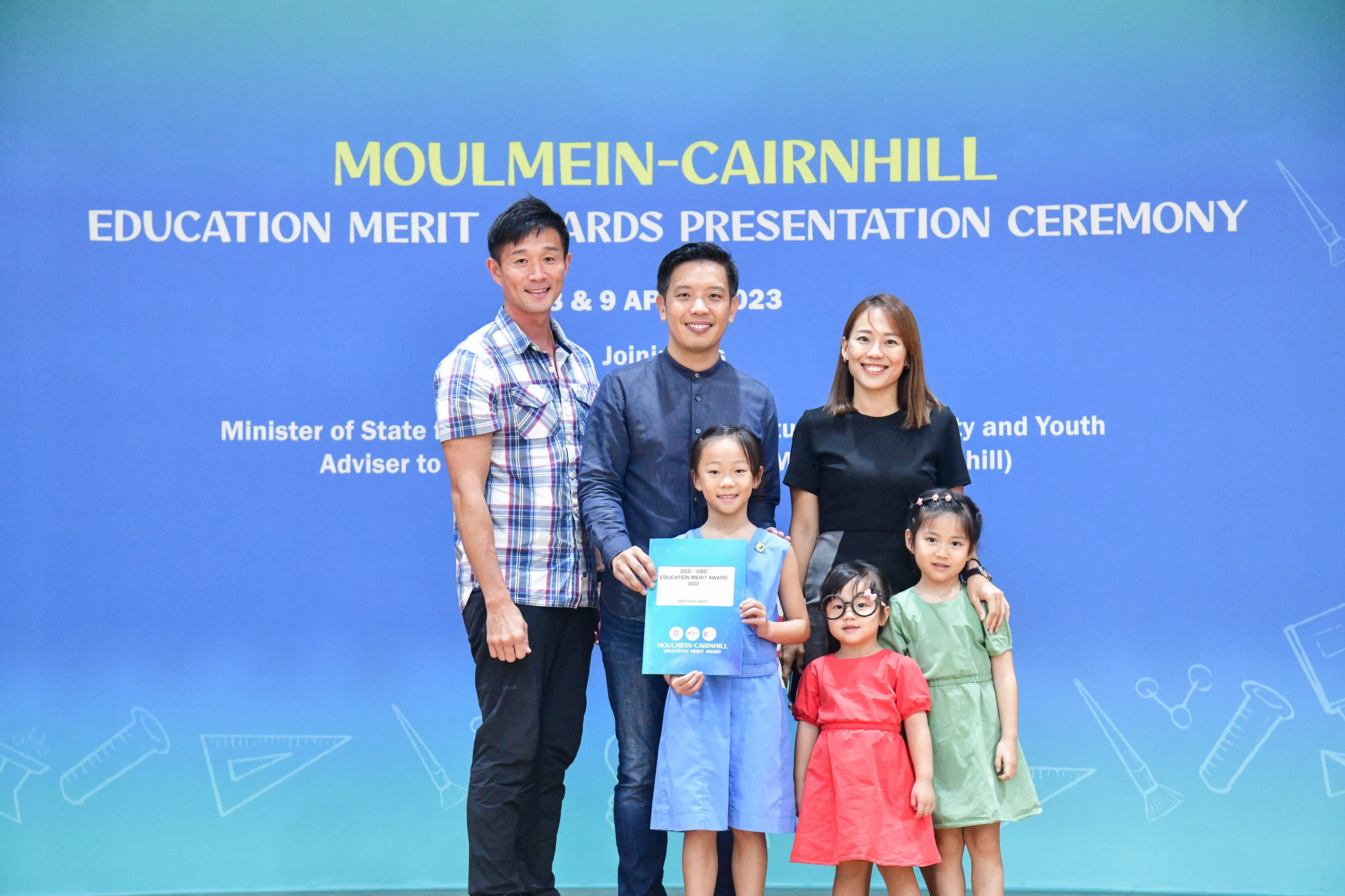 Two men, a woman, and three young girls pose at the Moulmein-Cairnhill Education Merit Awards Ceremony 2023.