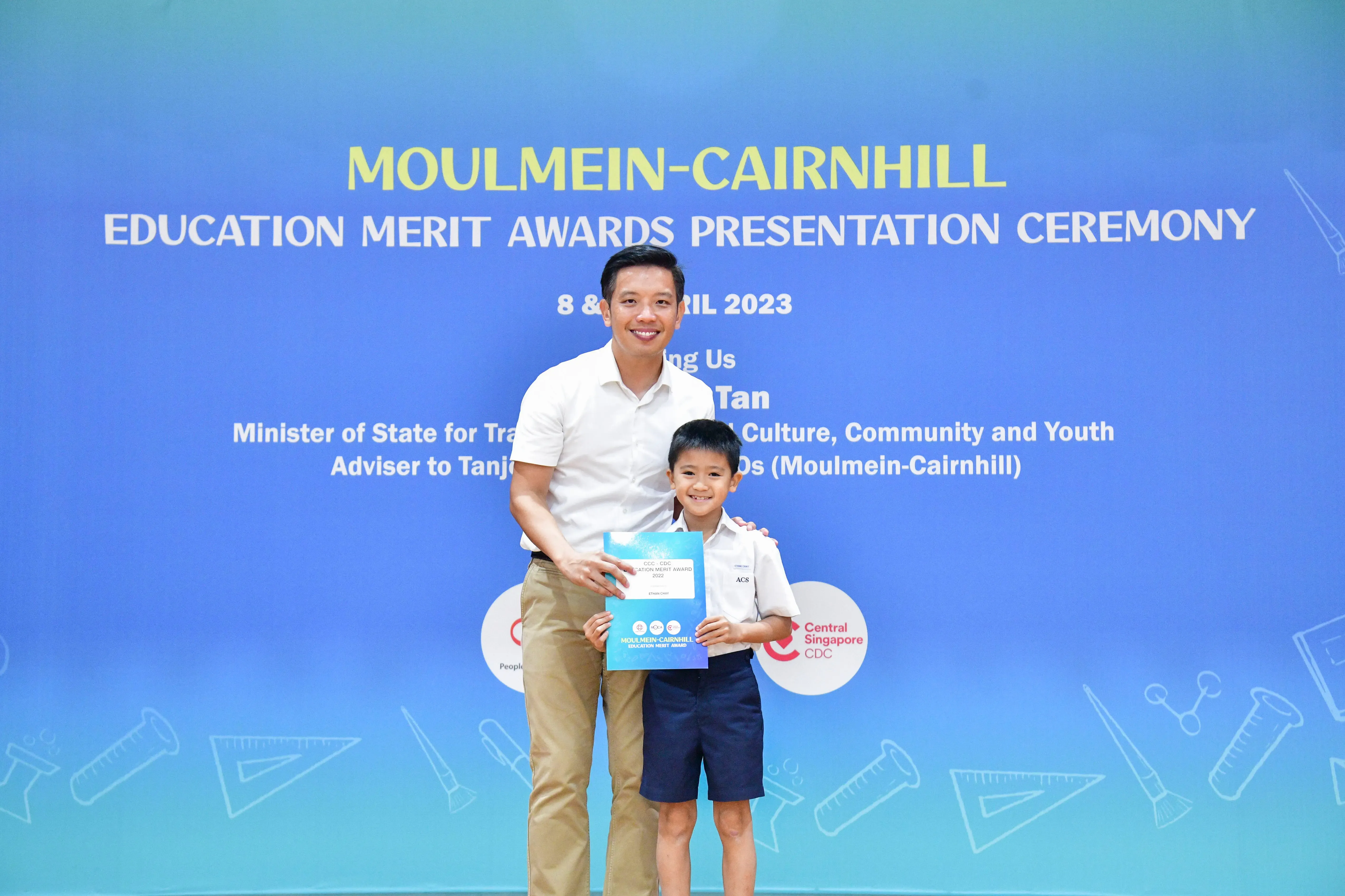 A man and a young boy pose holding an award certificate at the Moulmein-Cairnhill Education Merit Awards 2023.