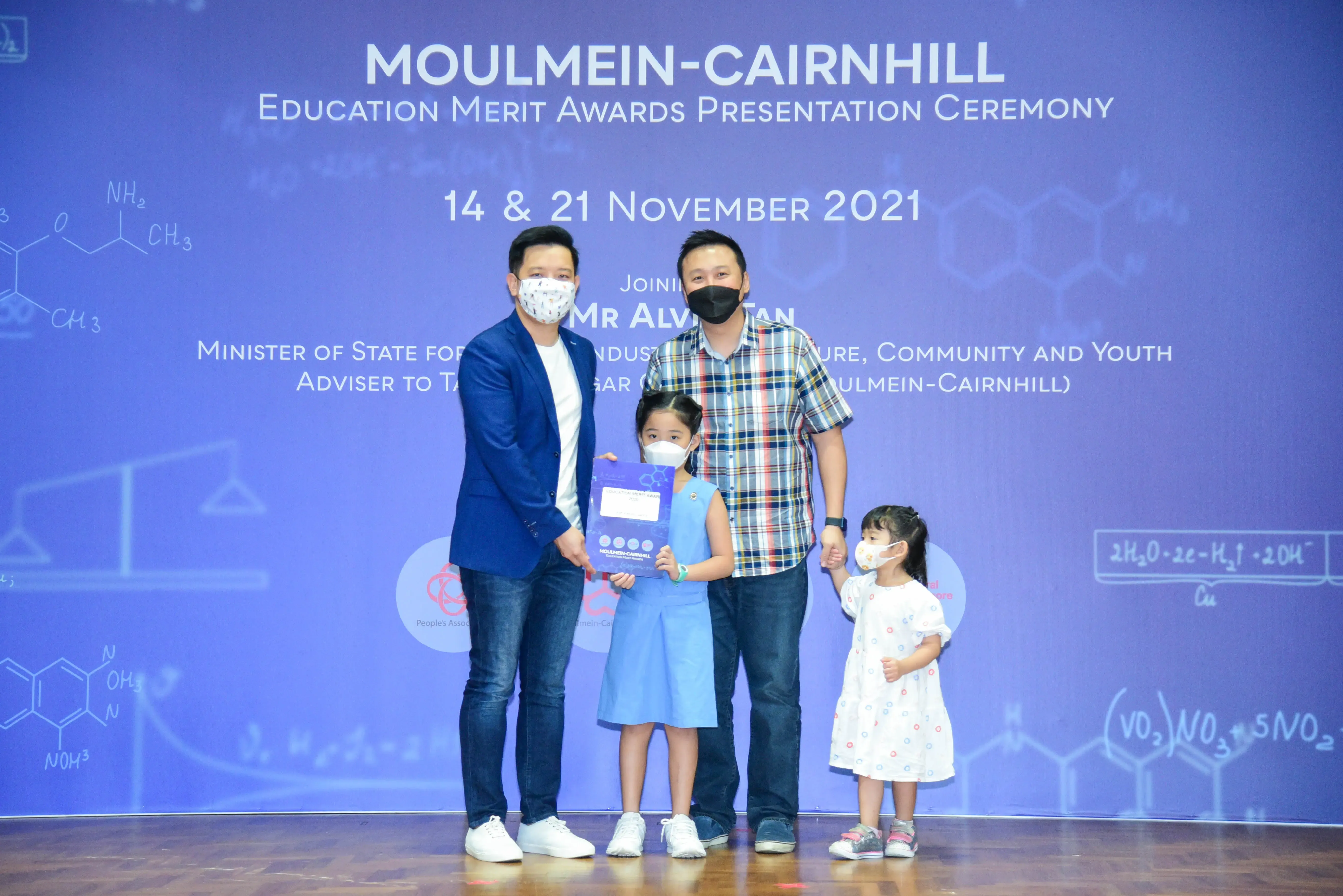 Two masked men and two young girls pose at the Moulmein-Cairnhill Education Merit Awards Ceremony, November 2021.