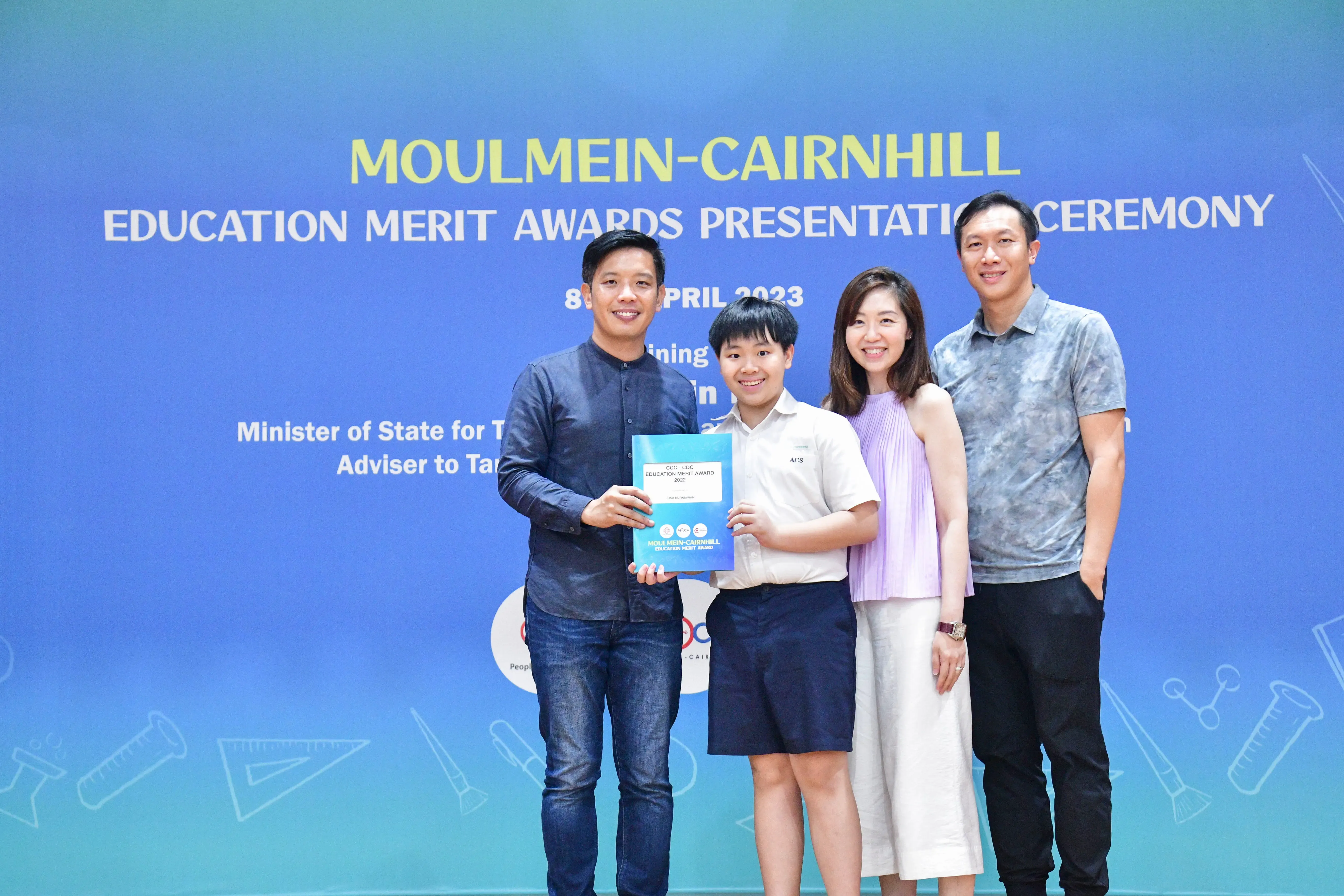 Four people pose at the Moulmein-Cairnhill Education Merit Awards Presentation Ceremony, holding a certificate.