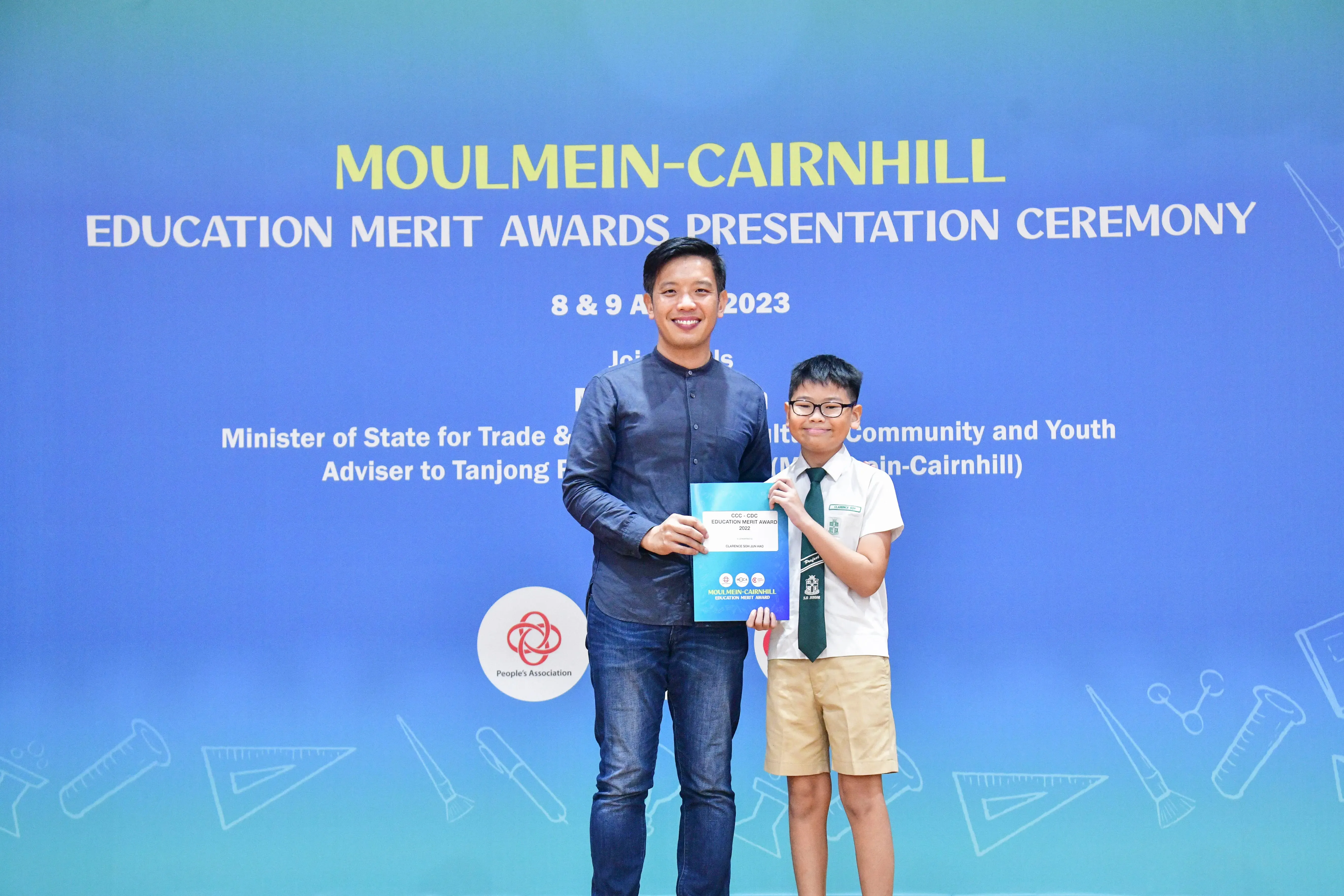 An adult and a young student in uniform hold a certificate at the Moulmein-Cairnhill Education Merit Awards 2023.