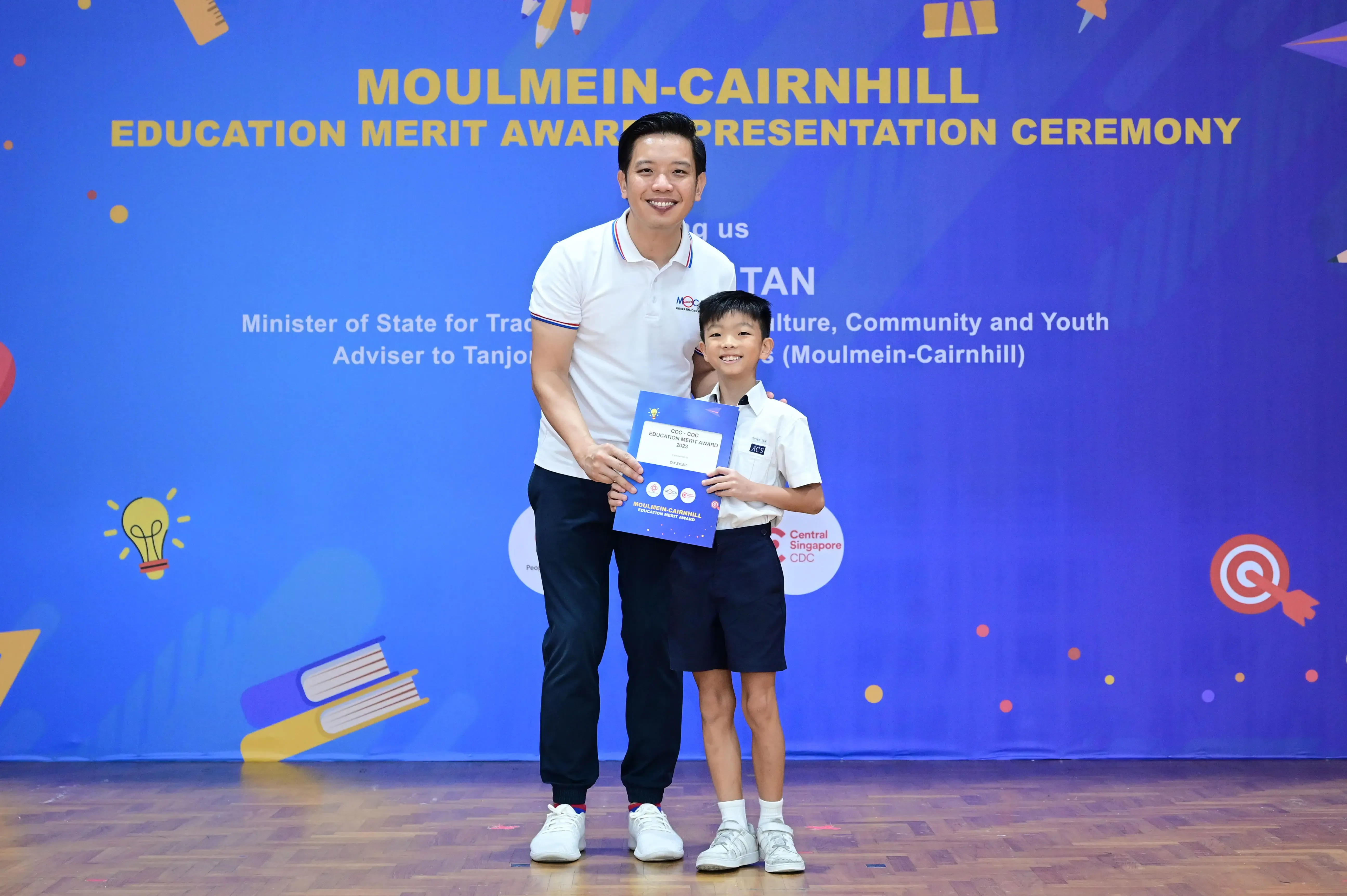 Man and young boy holding an award certificate at the Moulmein-Cairnhill Education Merit Award Presentation Ceremony.