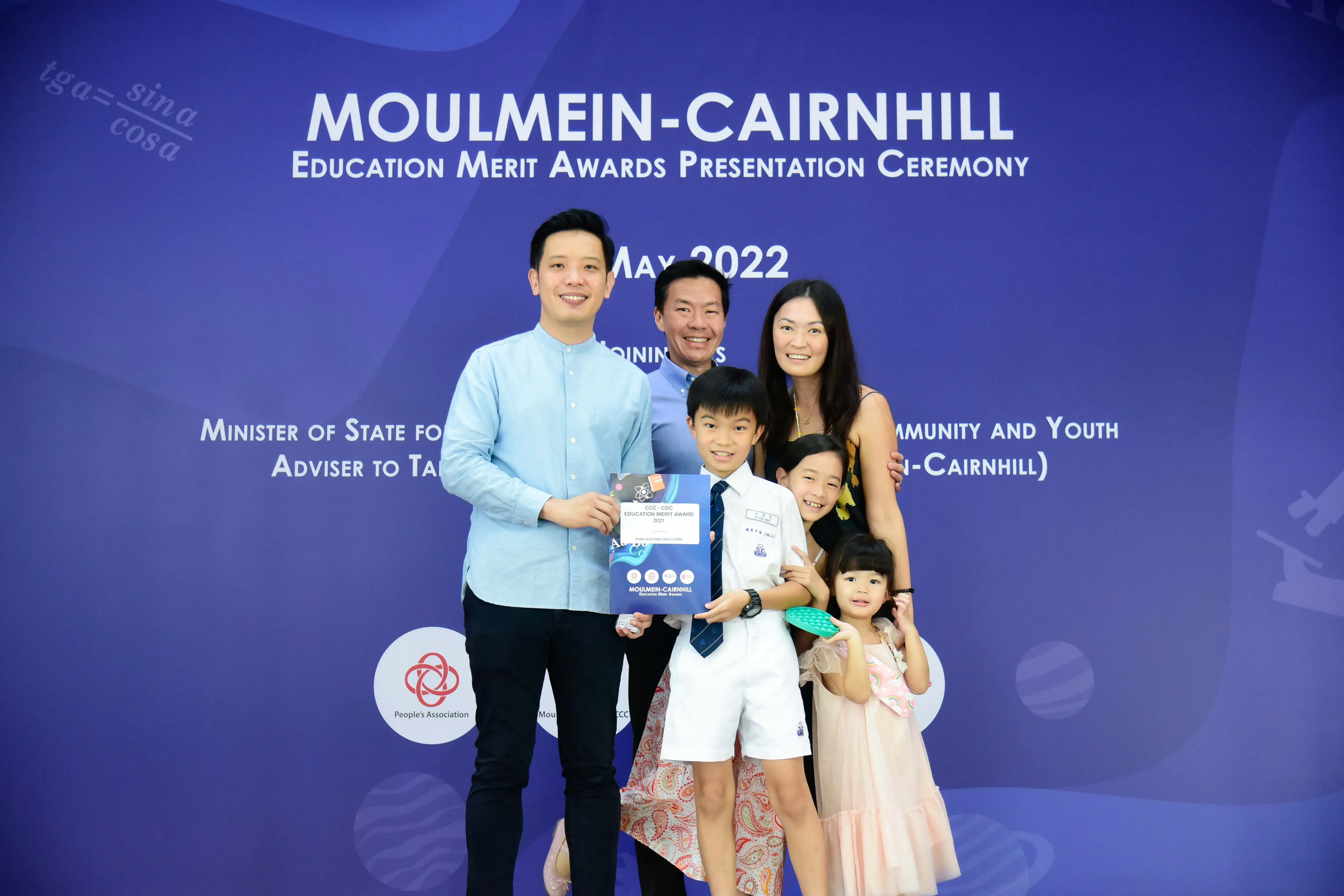 Family of five posing with an award certificate at the Moulmein-Cairnhill Education Merit Awards Ceremony, May 2022.