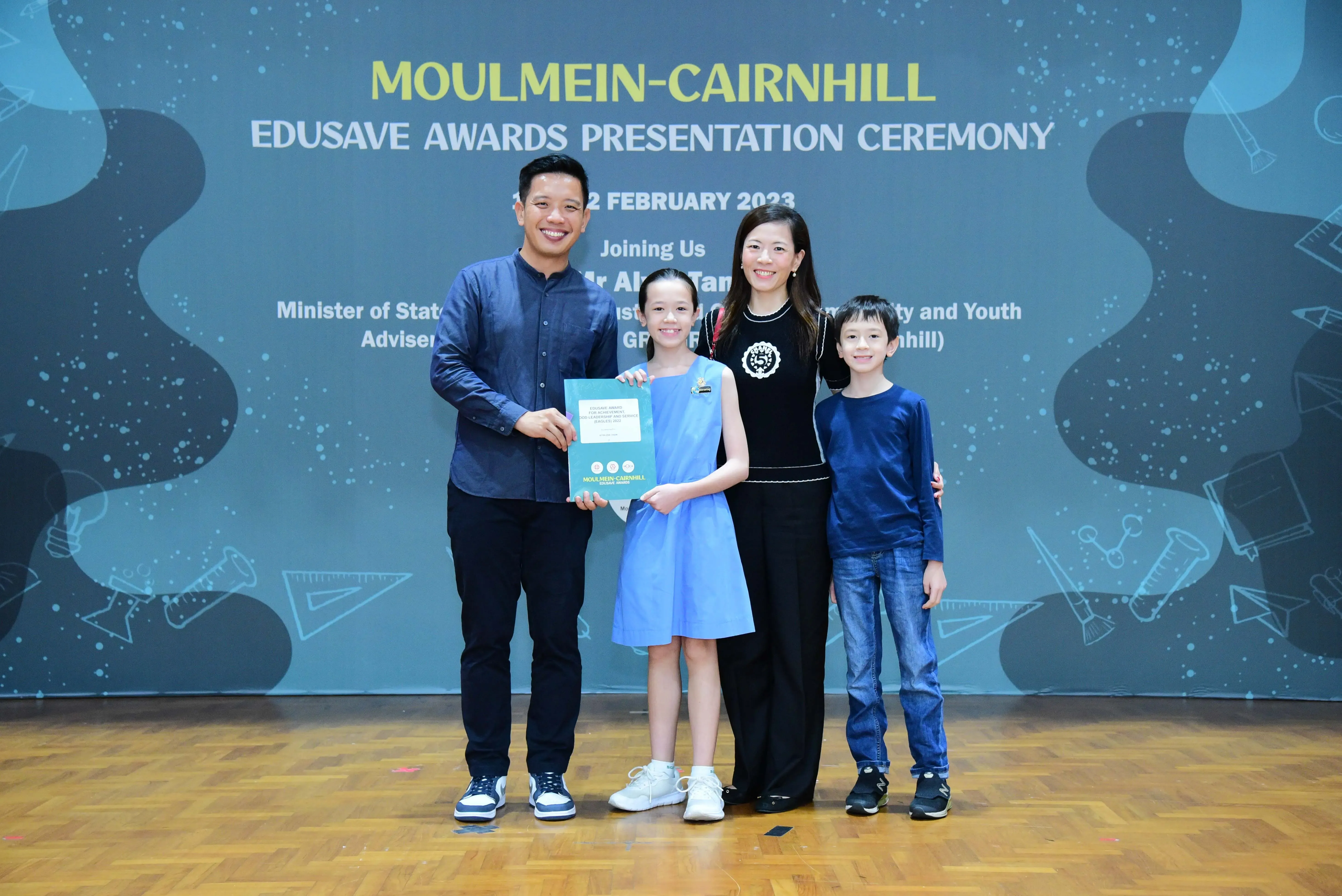 Family of four posing with an award at the Moulmein-Cairnhill Edusave Awards Presentation Ceremony, February 2023.