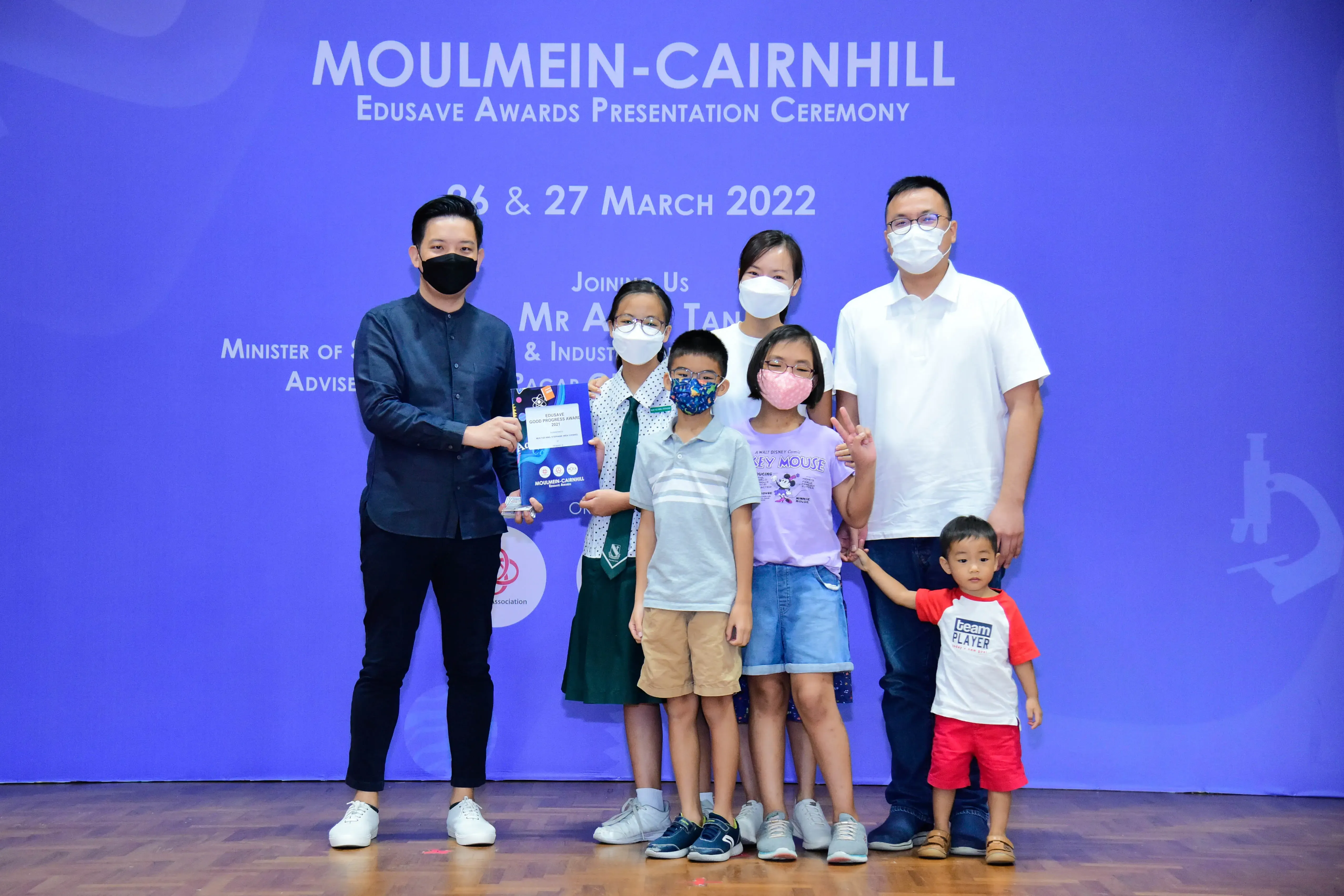 Adults and children in masks pose at the Moulmein-Cairnhill Edusave Awards Presentation Ceremony, March 2022.